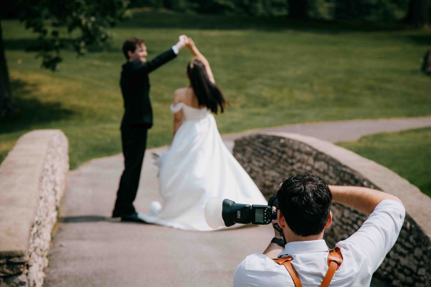 Andrey Boltyansky taking a photo of a couple on their wedding day, dancing on a bridge at a golf club.