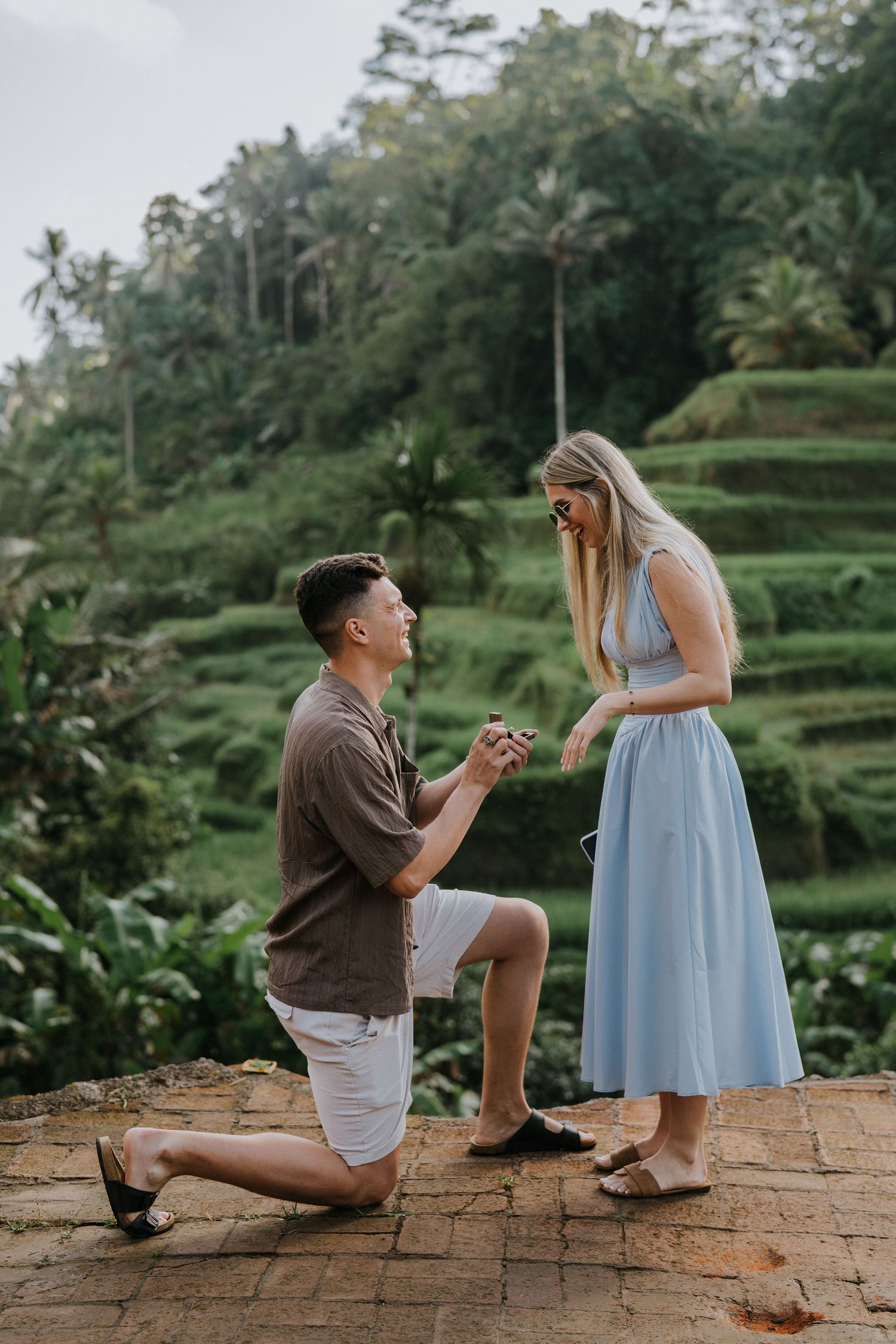 Couple walking along a green garden pathway surrounded by tropical plants.