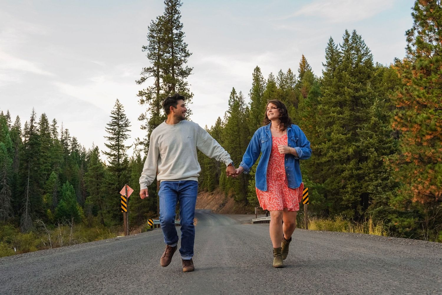 Two children running down a tree-lined road in a forest, arms outstretched, enjoying a carefree outdoor adventure.