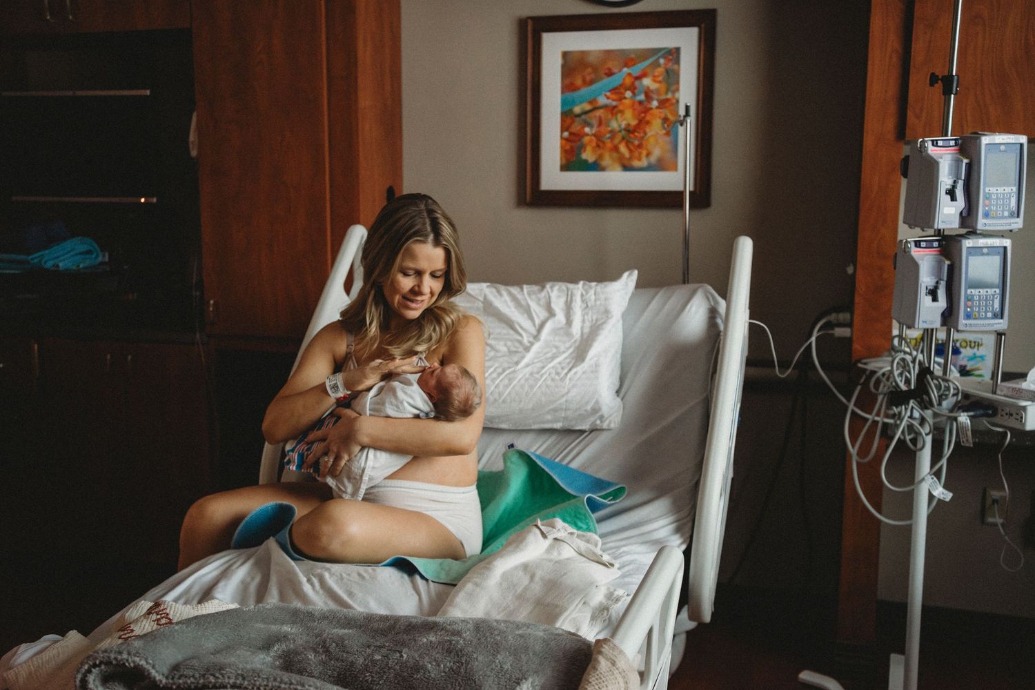 Patient rests in hospital bed while holding newborn baby in tender moment.