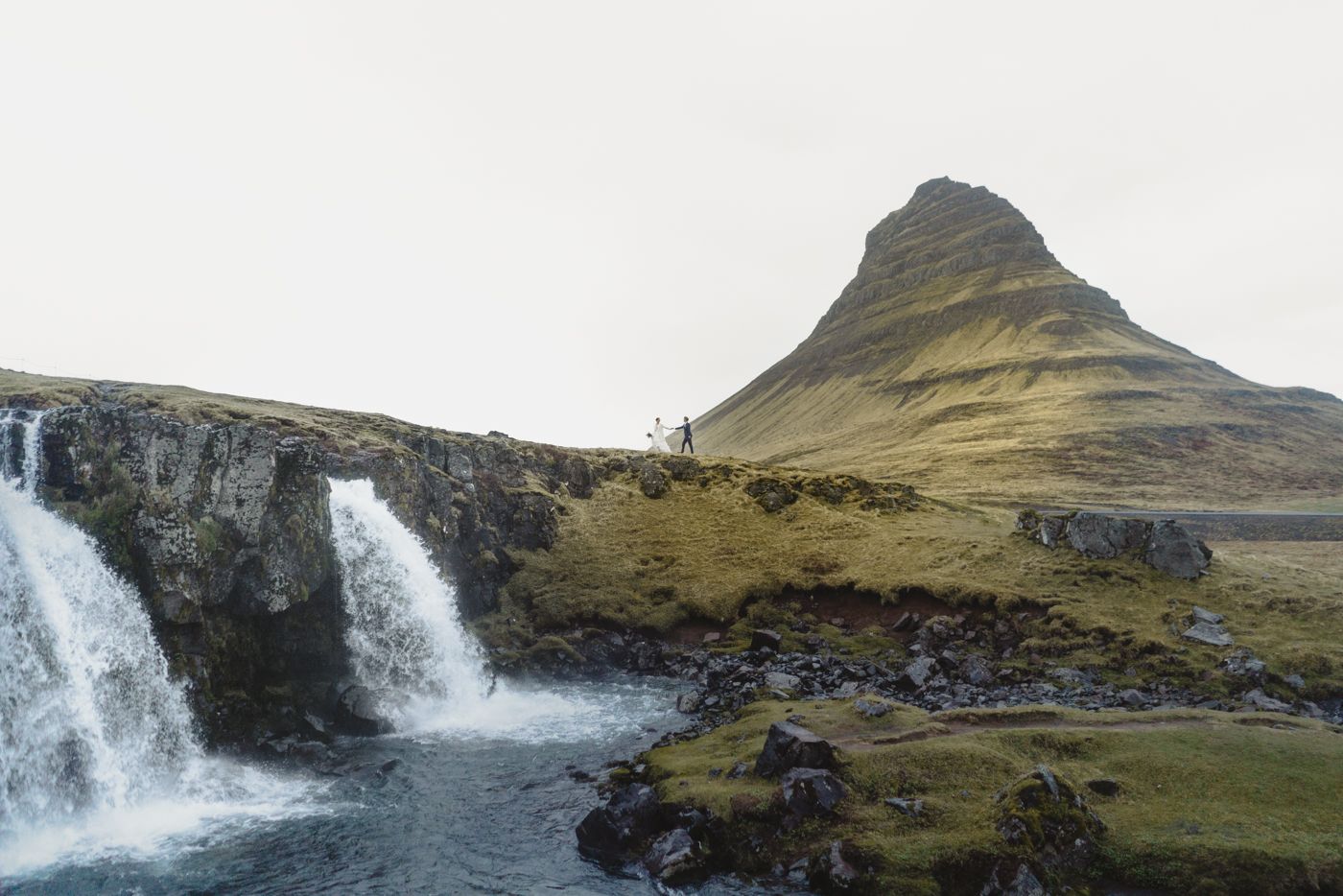 Couple walking in front of Kirkjufellfoss