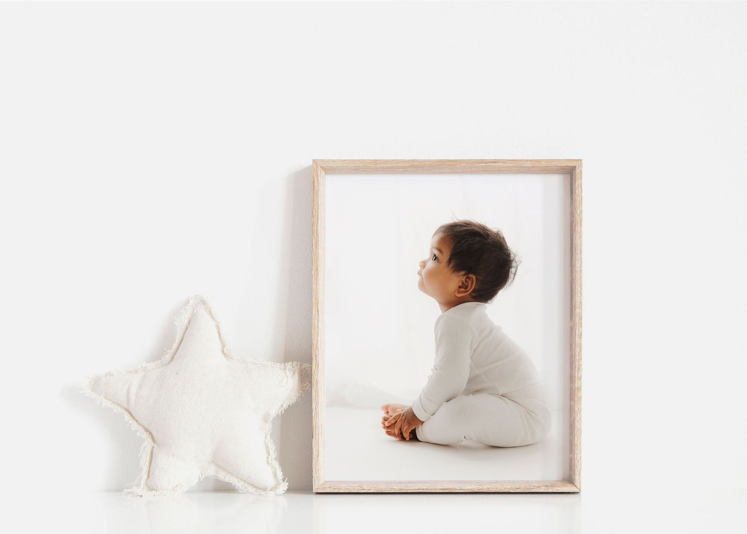 Minimalist nursery decor featuring white star cushion and framed artwork.