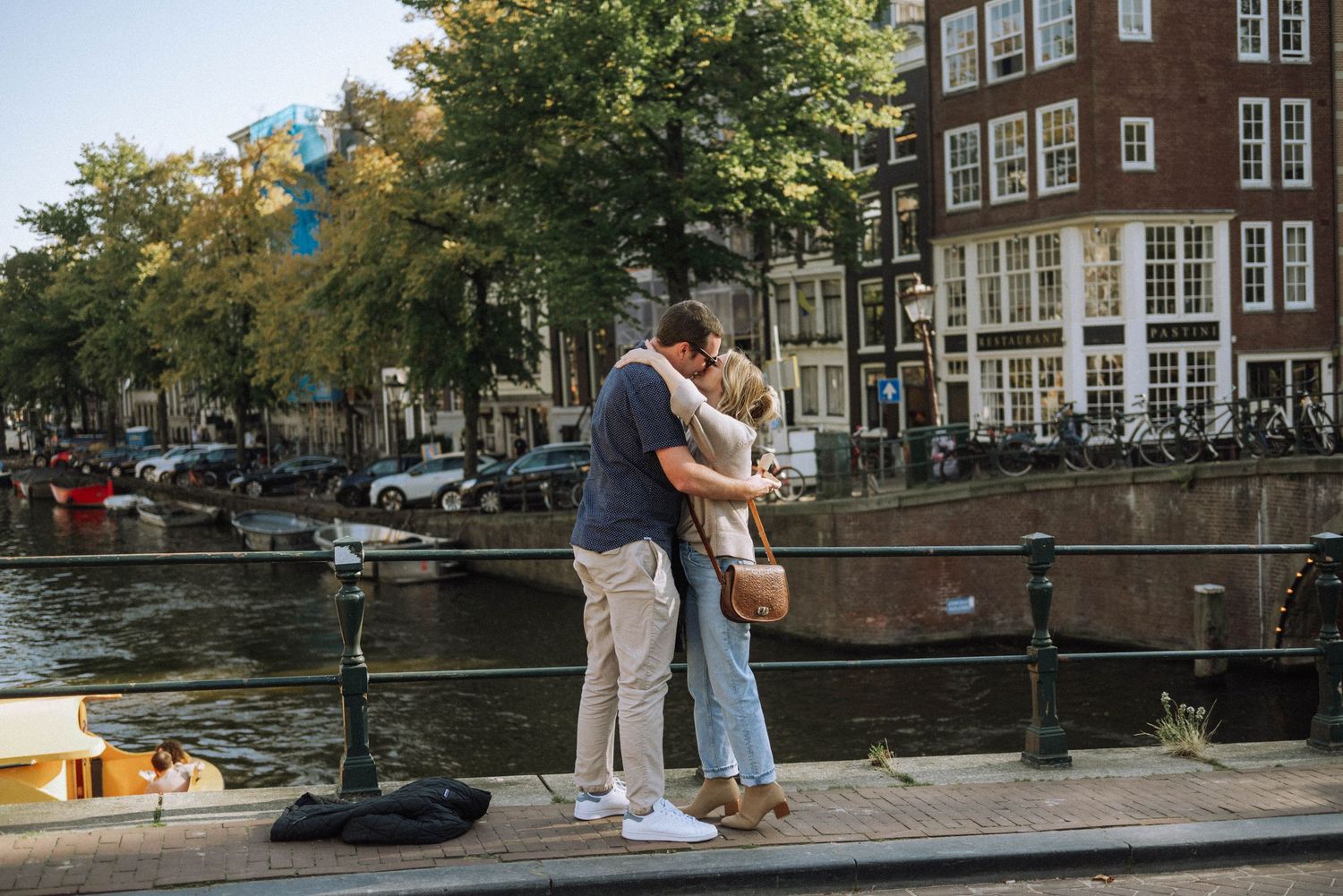 The moment of a surprise marriage proposal on a wide bridge in Amsterdam with sunlight streaming through.