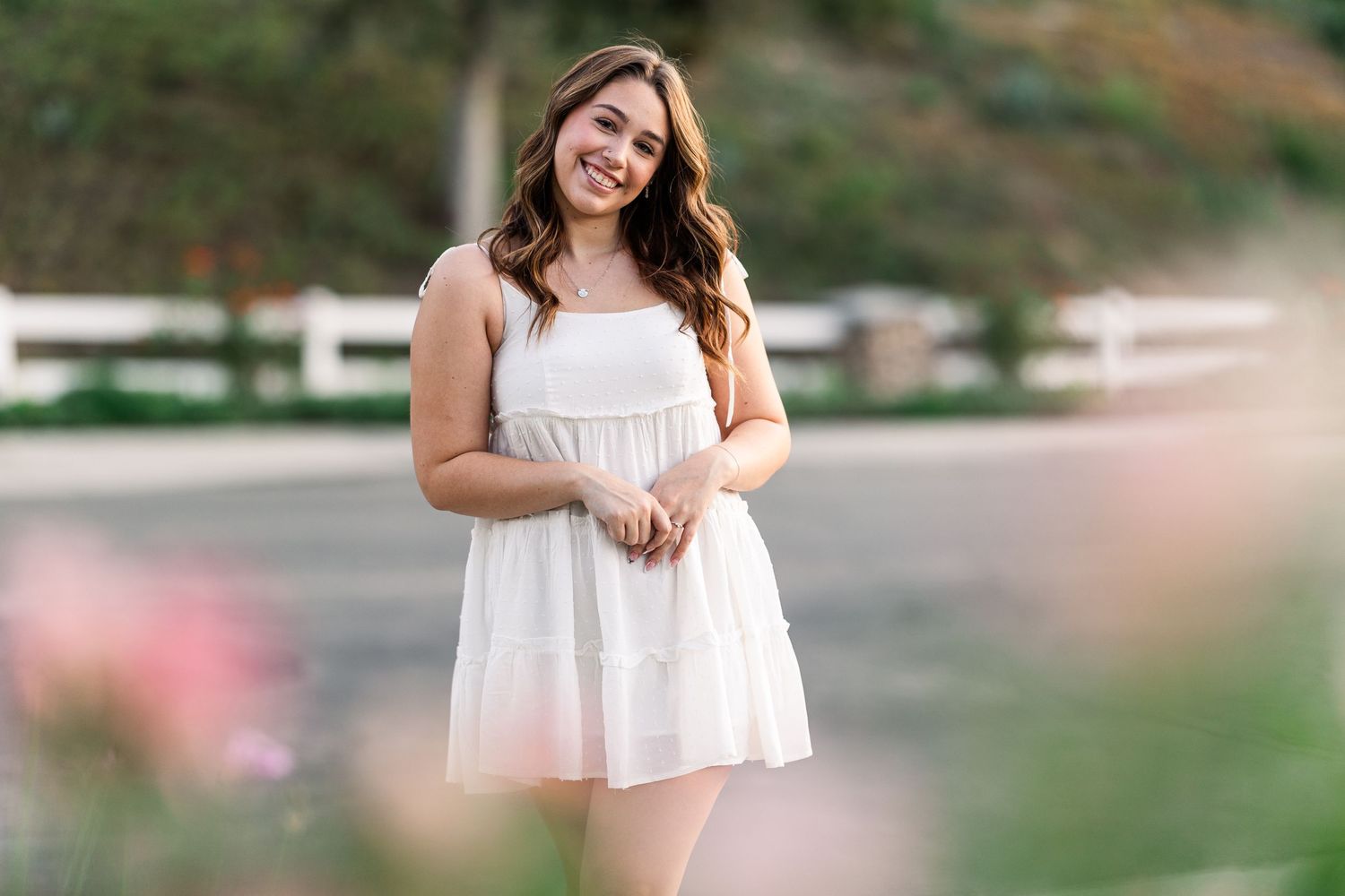 Soft portrait in white sundress against blurred natural background.