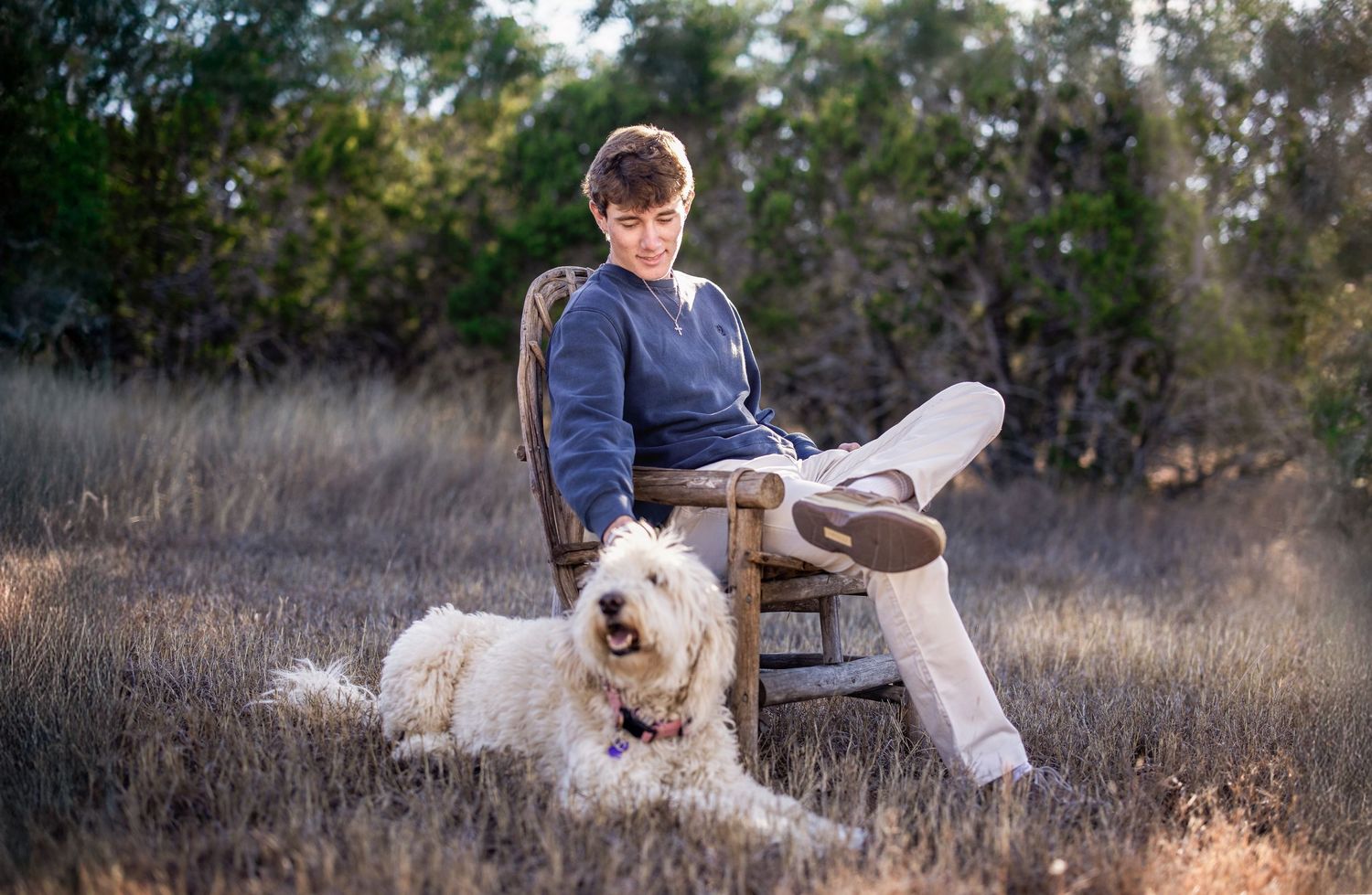 A white dog and her owner playing together in a grassy field during golden hour lighting.
