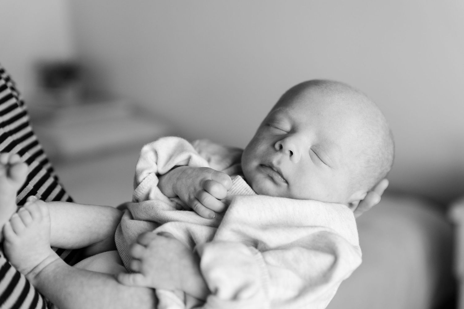 st. George utah photographer captures black and white 1 month old baby sleeping mom holding him outstretched wearing an oversized sweater
