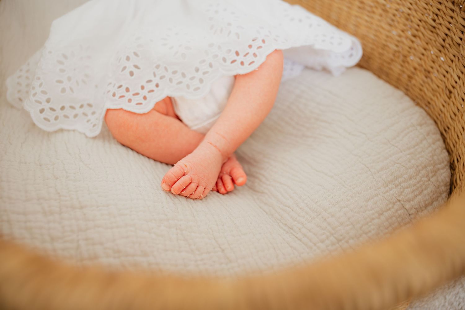 Close up of tiny baby feet resting on white textured blanket.