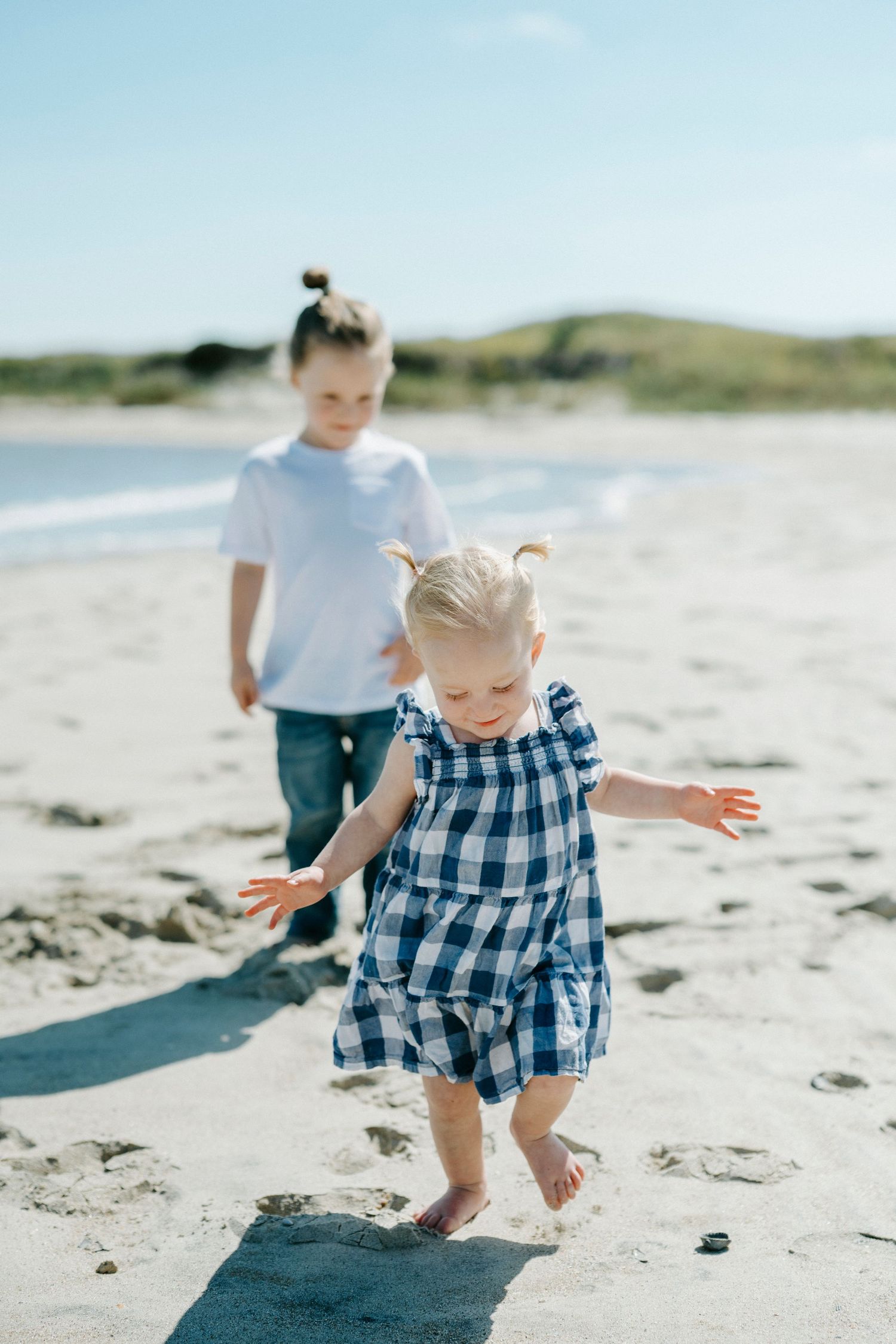 Children playing and exploring together on a sunny beach with soft white sand and natural coastal scenery.