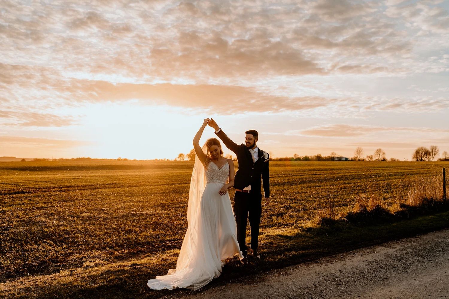 Wedding ceremony setup in rustic wooden barn with white floral arrangements and natural lighting.