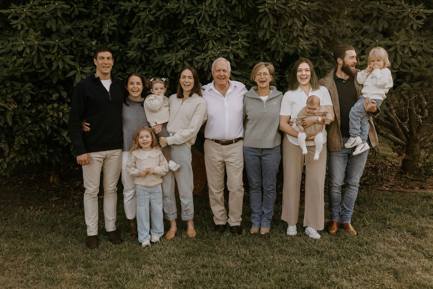 A series of seven casual outdoor family portraits taken in a natural setting with people wearing coordinated neutral colors.
