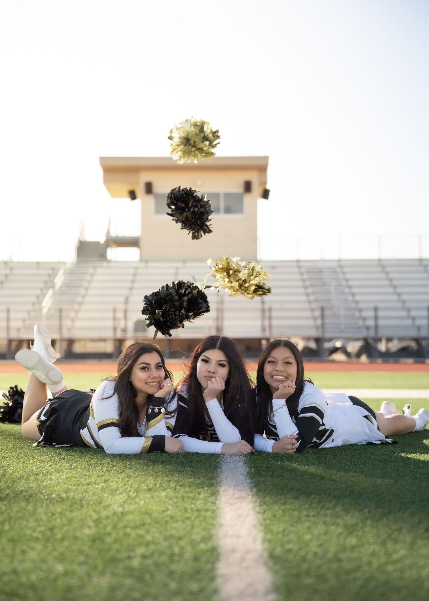 Cheerleaders tossing pom-poms in the air during outdoor group portrait