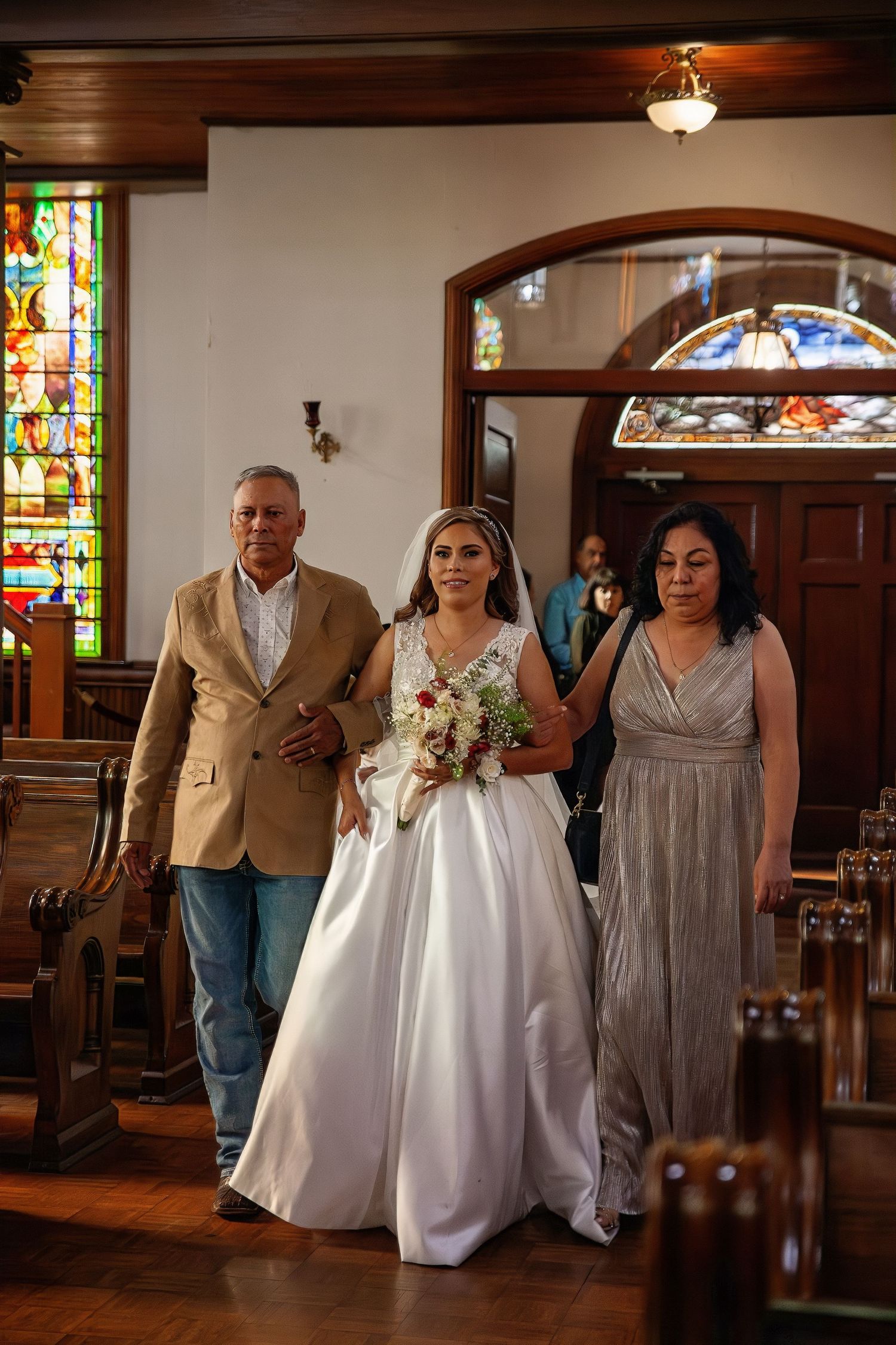 Wedding ceremony in historic church with stained glass windows and wooden beams.
