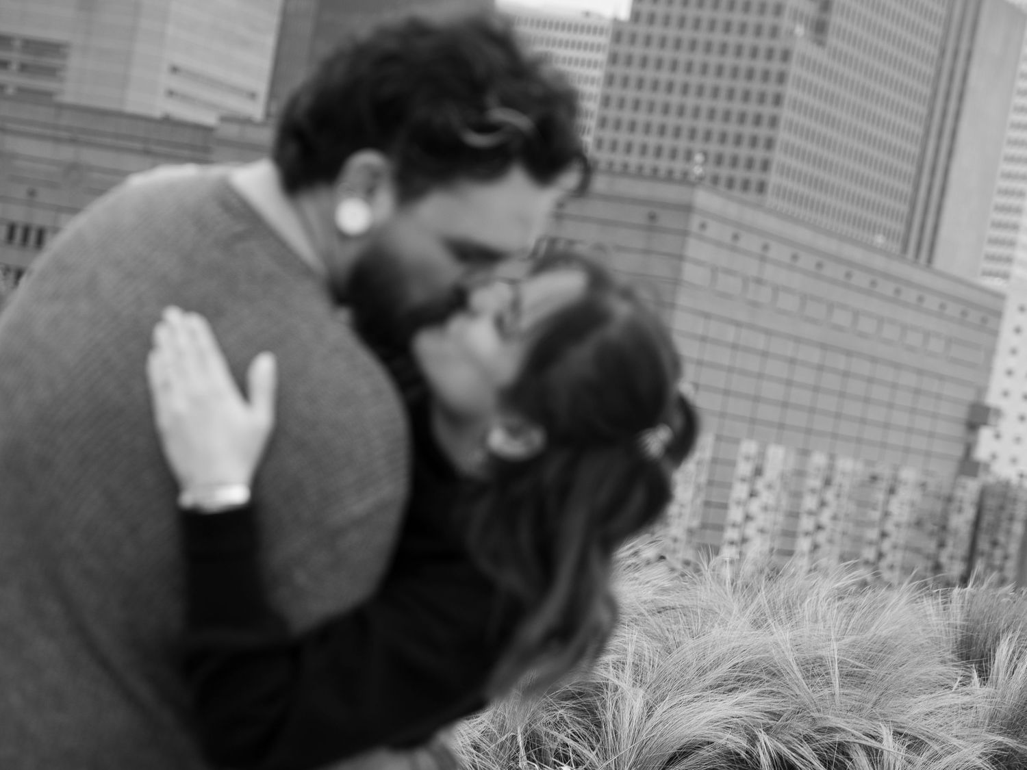 Two people sit at the edge of a curved concrete wall while having a conversation in an outdoor setting.