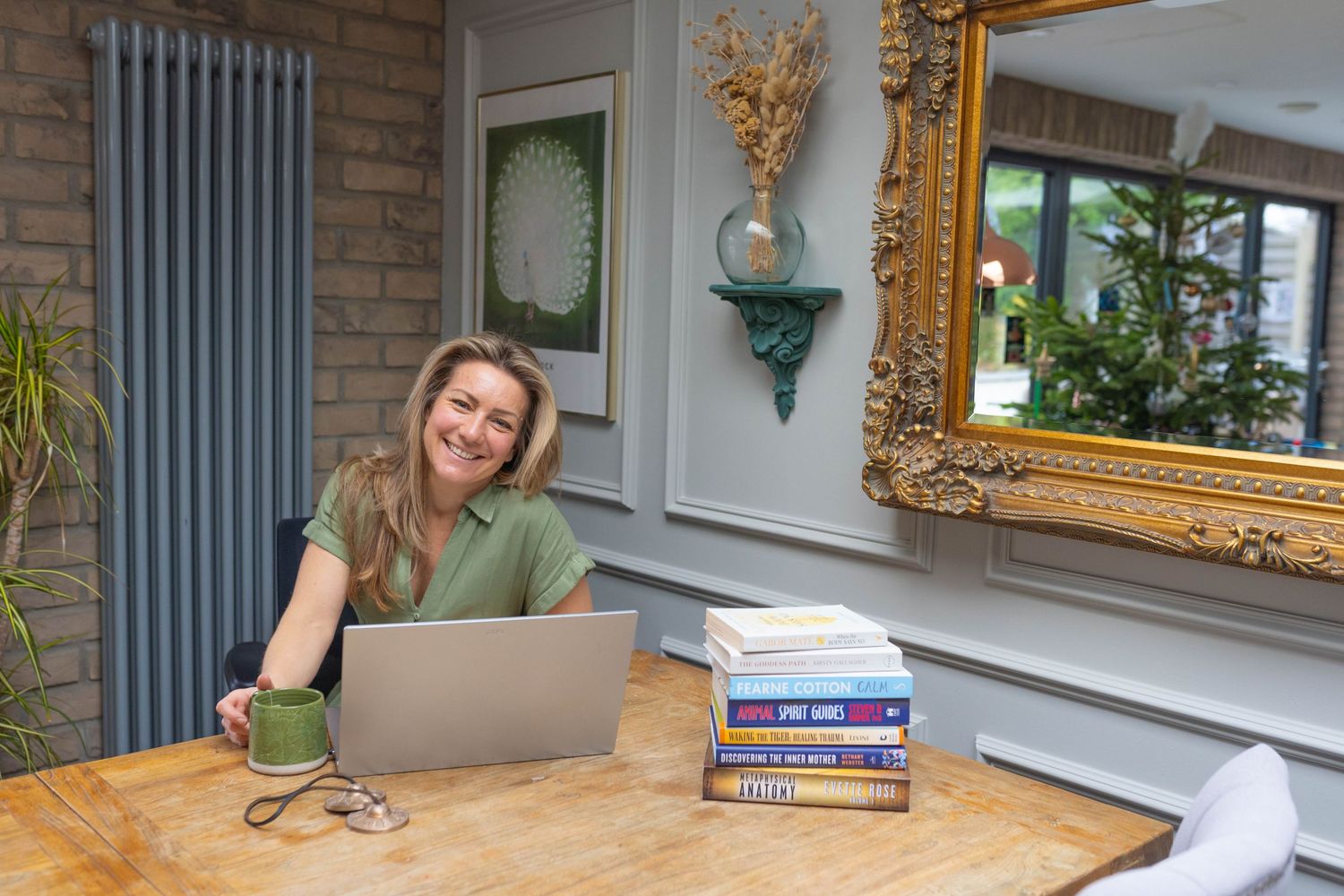 personal branding photography Brighton of a therapist sat at her desk in a green dress with her lap top open and books on the desk