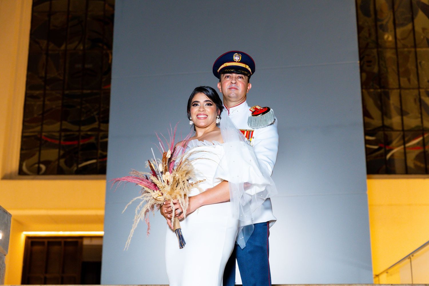 Pareja de novios, Lina y Nestor, avanzando juntos bajo un arco de espadas en su elegante ceremonia de boda en la Catedra