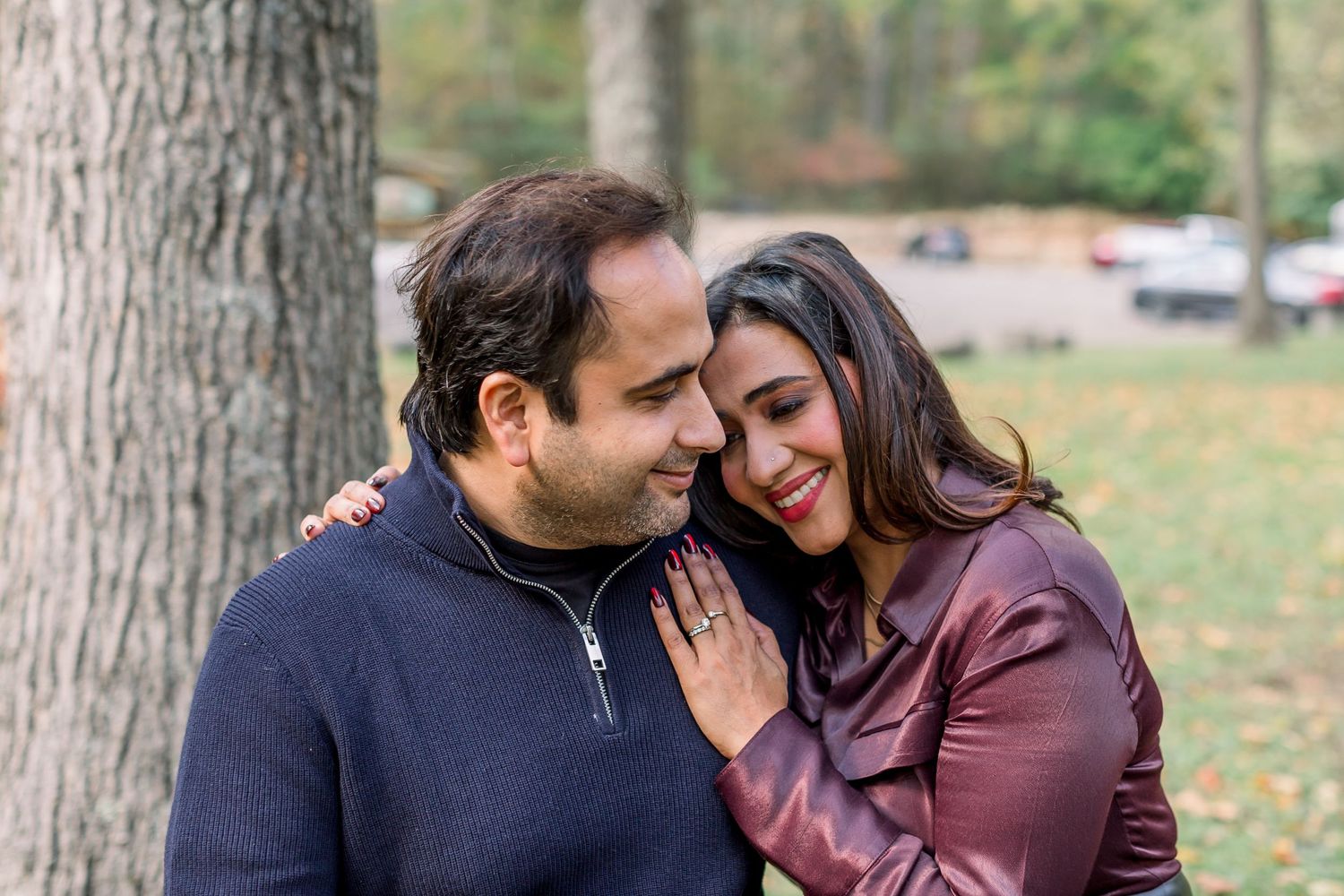 Romantic couple sharing intimate moments against a tree trunk backdrop.