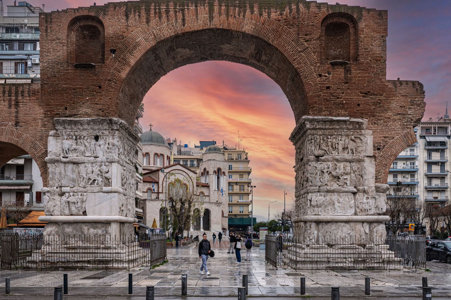 The Arch of Galerius, a Roman triumphal arch in Thessaloniki, Greece, stands majestically against a vibrant sunset sky.