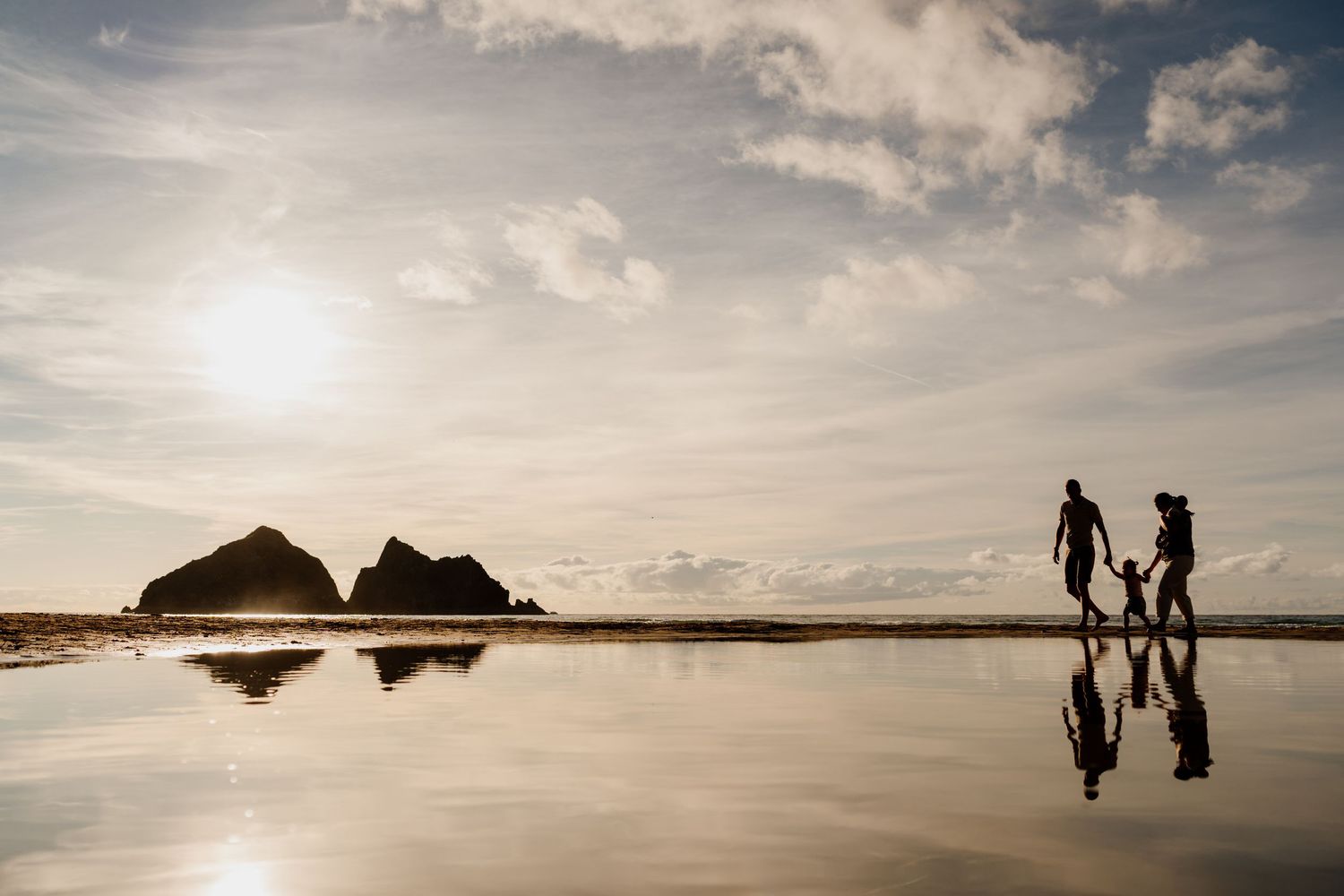 Adult tossing a child high into the blue sky at Godrevy beach during family photoshoot