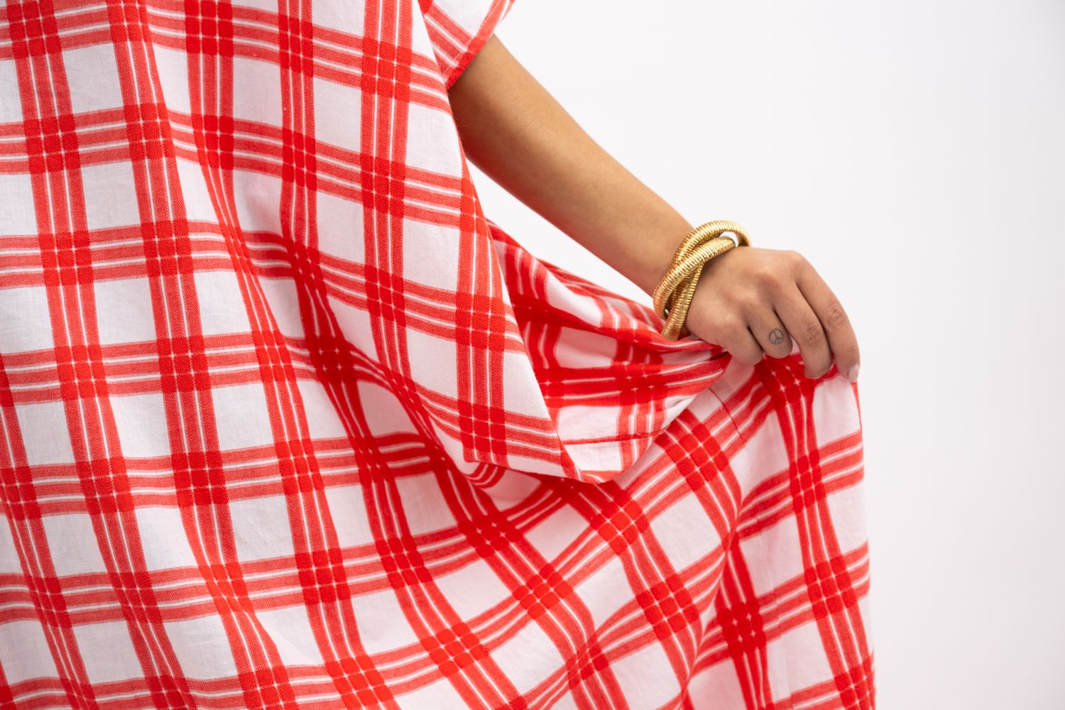 Two women posing together, one in red plaid with head wrap, other in lime green top, against white background.