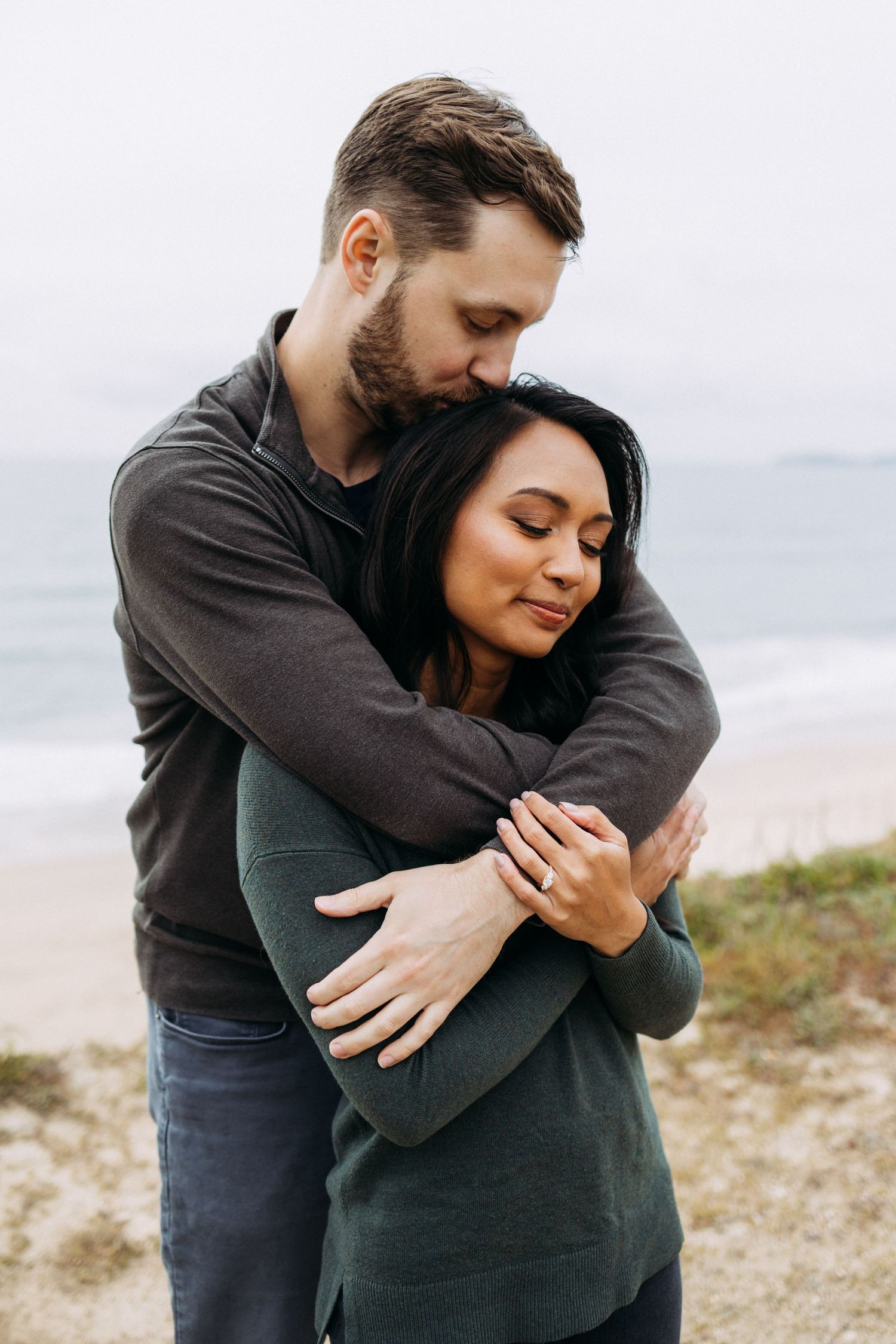 Biracial couple embraces during Half Moon Bay engagement pictures