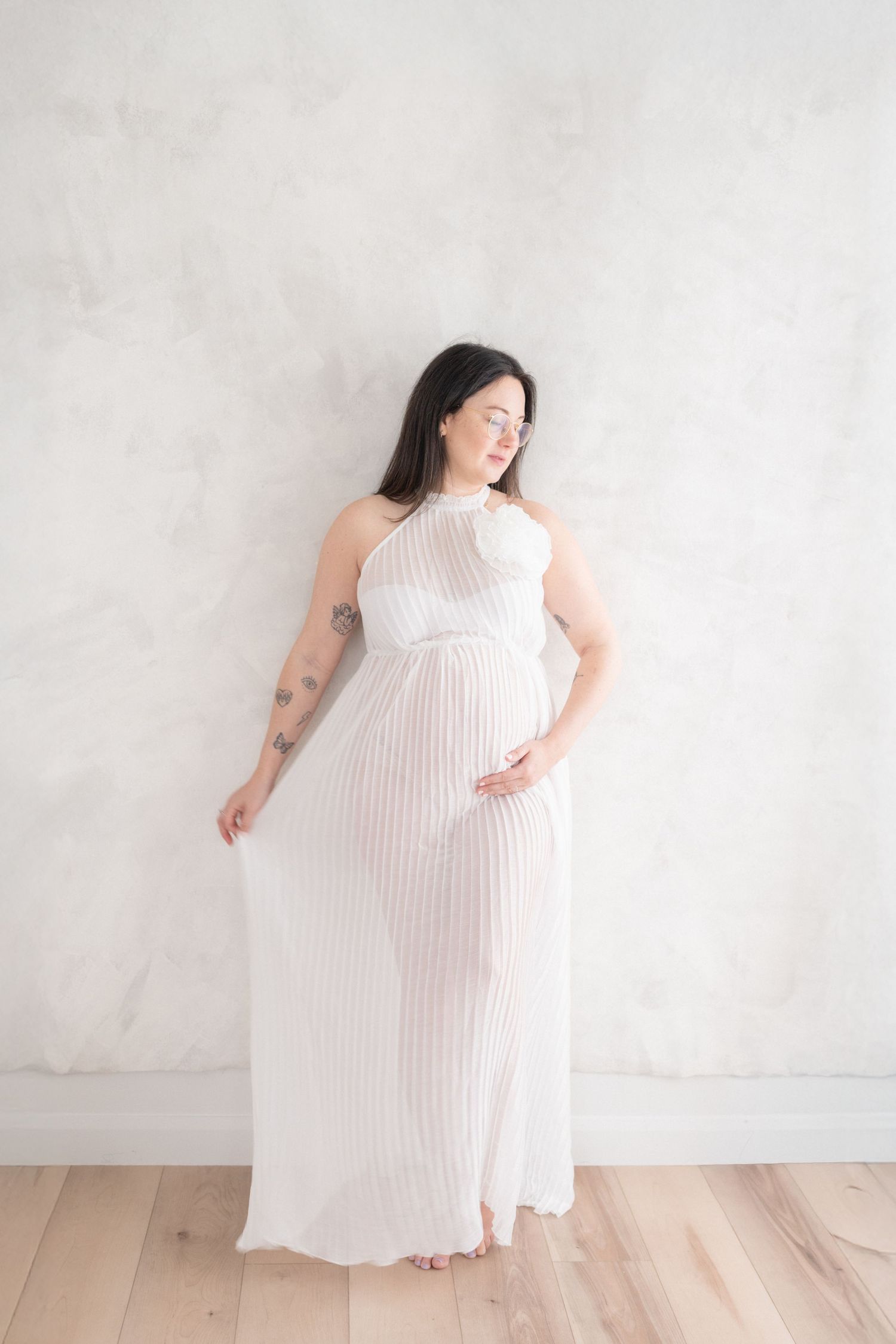 Future maman dans une robe blanche et vaporeuse dévoilant ses épaule et son ventre rond