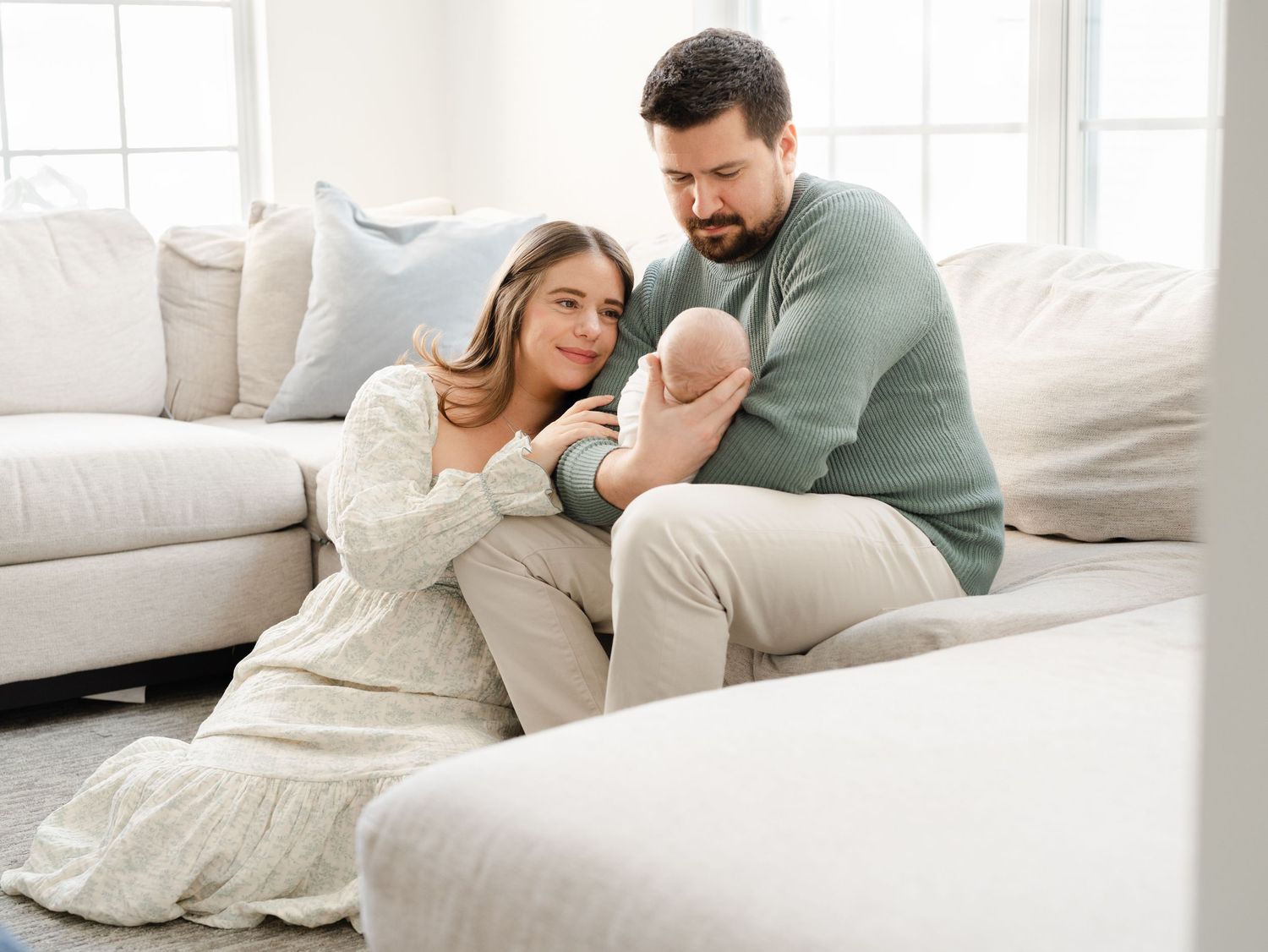 A mother and father sits in the family room holding their newborn baby boy during a monmouth county photo session.