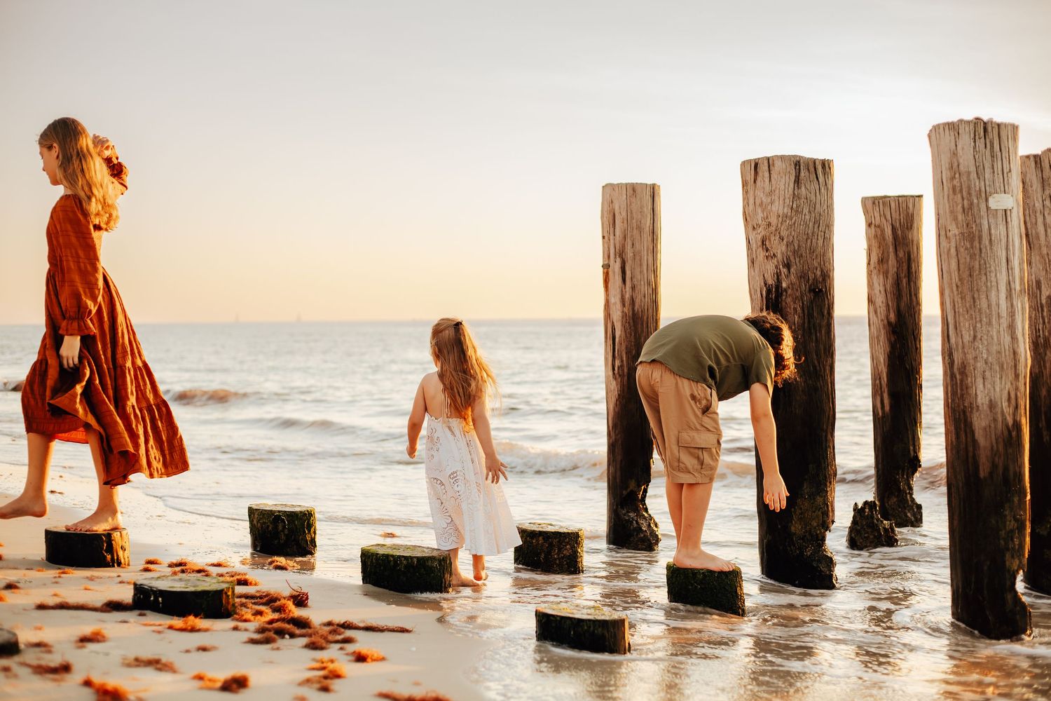 Family members sit together on a wooden bridge during a sunset photo session in a park.