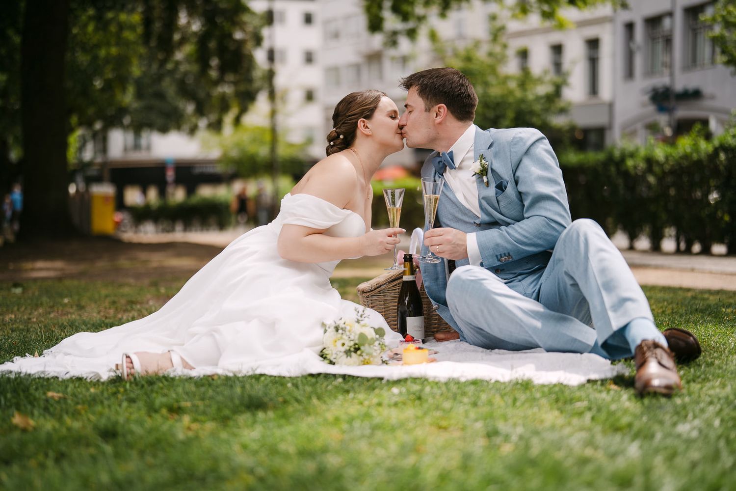 Romantic kiss on picnic blanket in Aachen’s Elisengarten of a recently married couple.