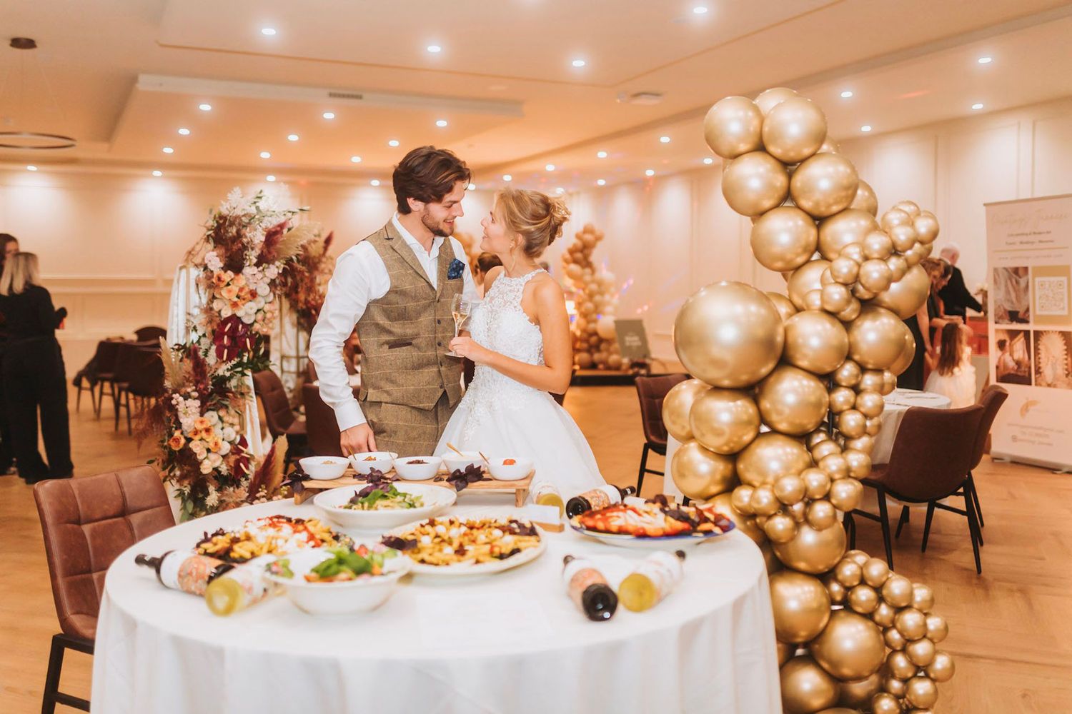 Elegant wedding reception at BLOQ23 in Hoofddorp decorated with golden balloon arrangements and white tablecloths for a wedding celebration.