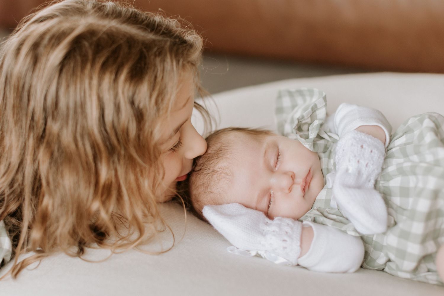 A series of intimate newborn baby photos showing gentle moments of bonding and sleeping in soft white bedding.