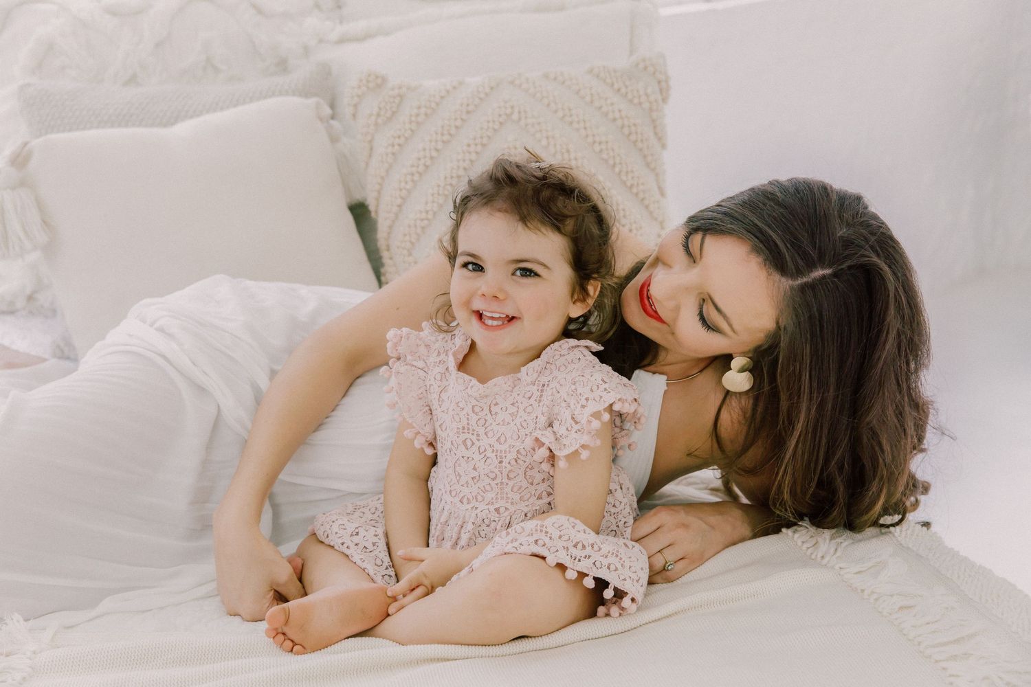 Four sweet moments of parent and child lying together on white bedding show tender bonding and affection.