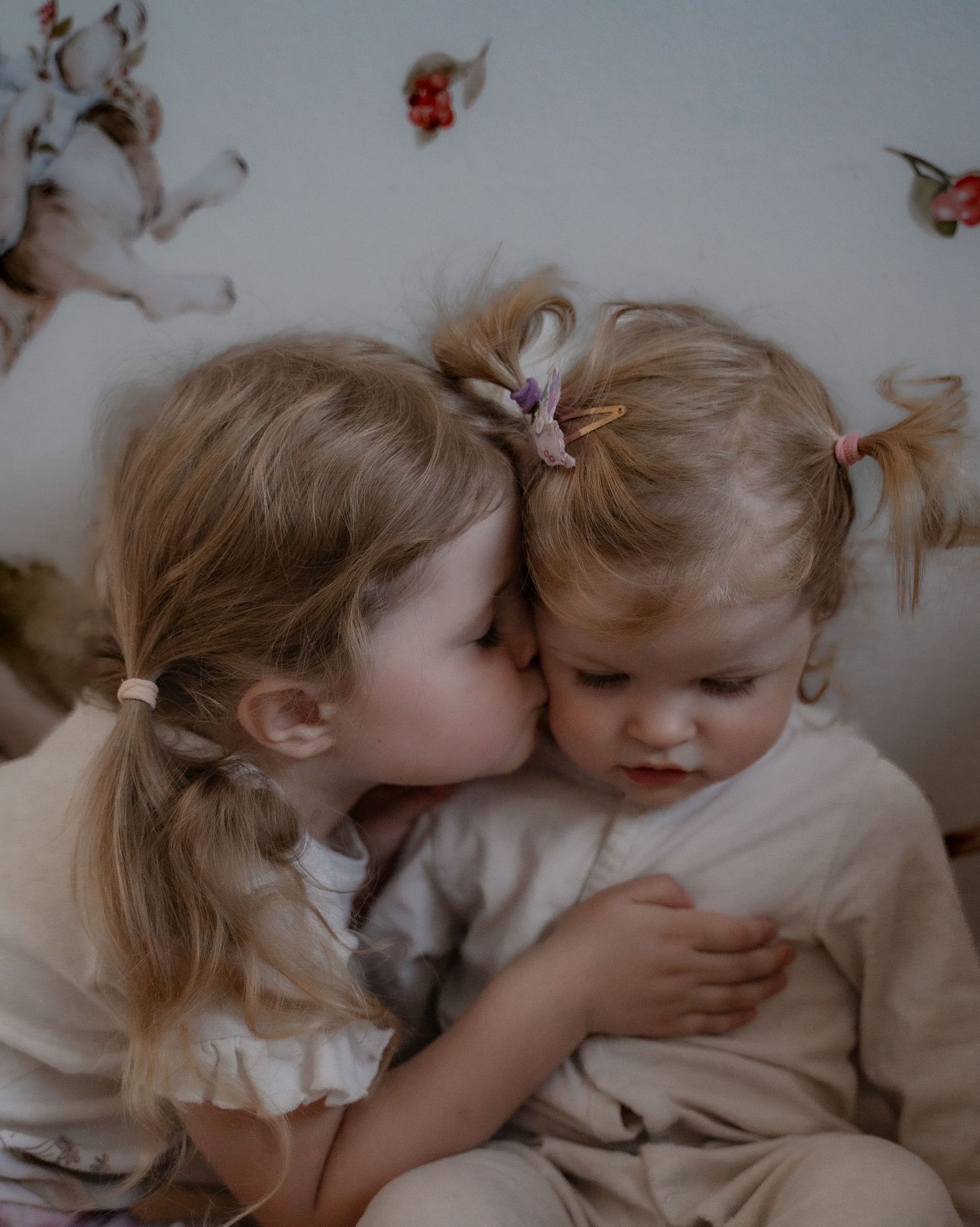 Big sister kissing her younger sibling on the head during an intimate lifestyle family photography session in Derbyshire.