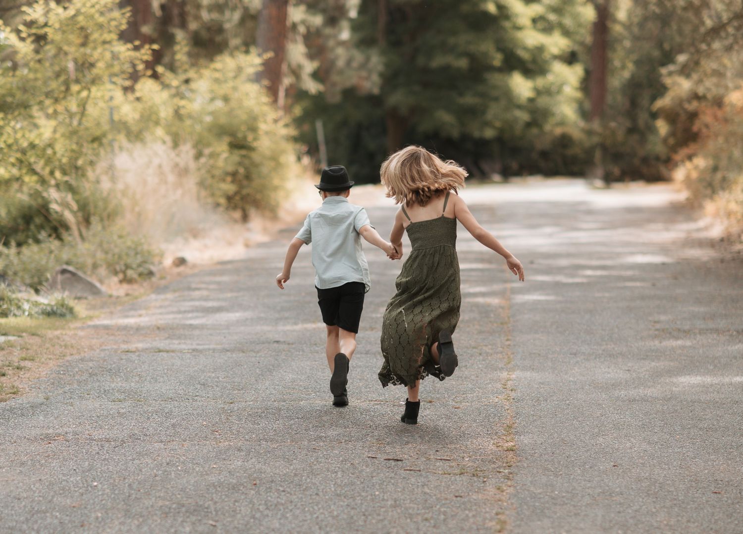 Young boy and girl running playfully at Spokane's Manito Park. Surrounded by fall colors and warm late summer air.