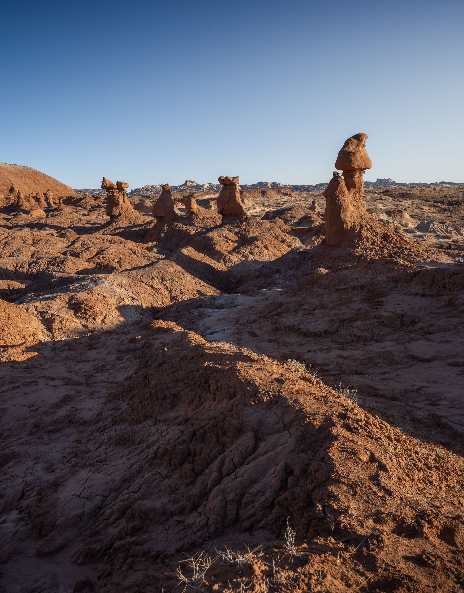 A series of silhouetted figures stand against a sunset sky viewed through natural rock arches in a desert landscape.