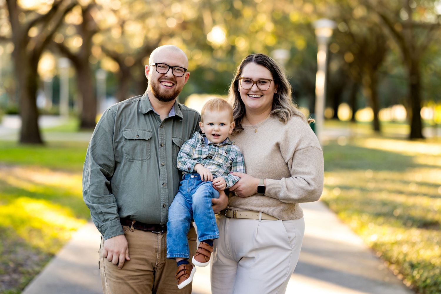 Family portrait taken on a tree-lined path during golden hour.