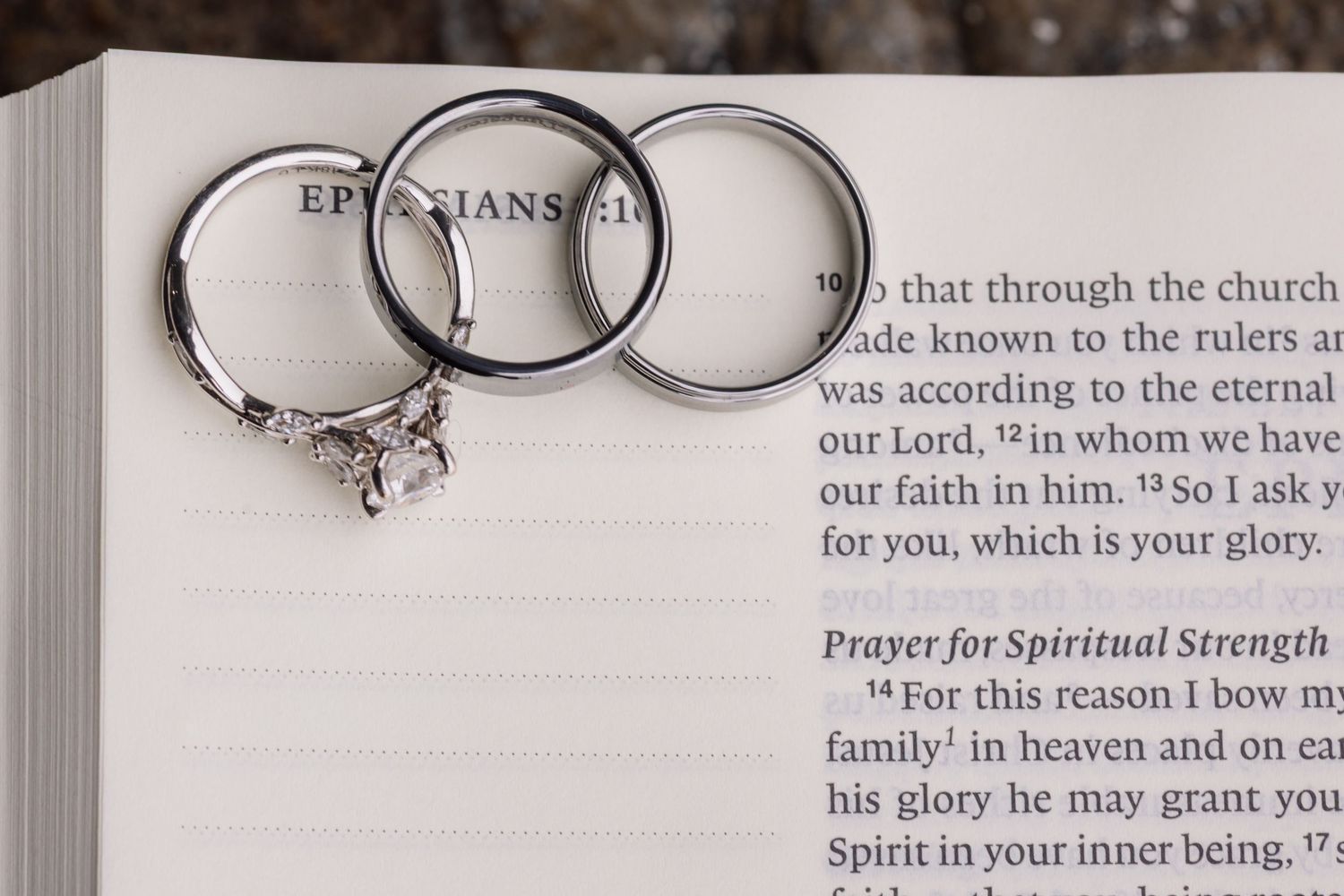 Wedding rings rest on an open book page with text about spiritual strength and prayer.
