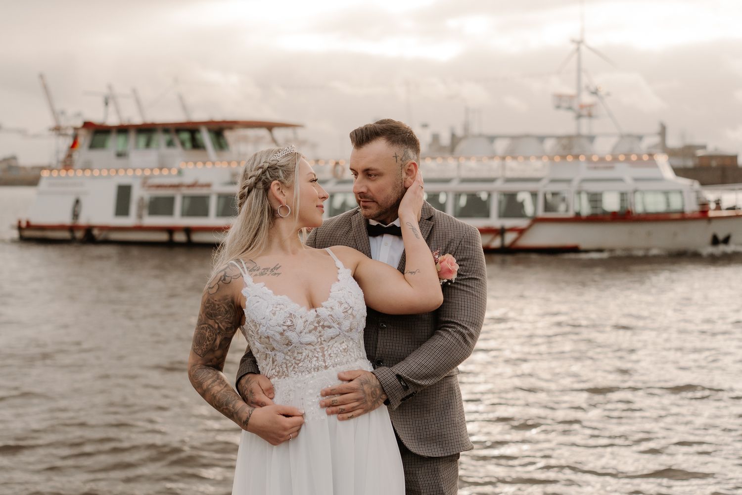 A romantic wedding couple embraces in sunlit garden setting at golden hour.
