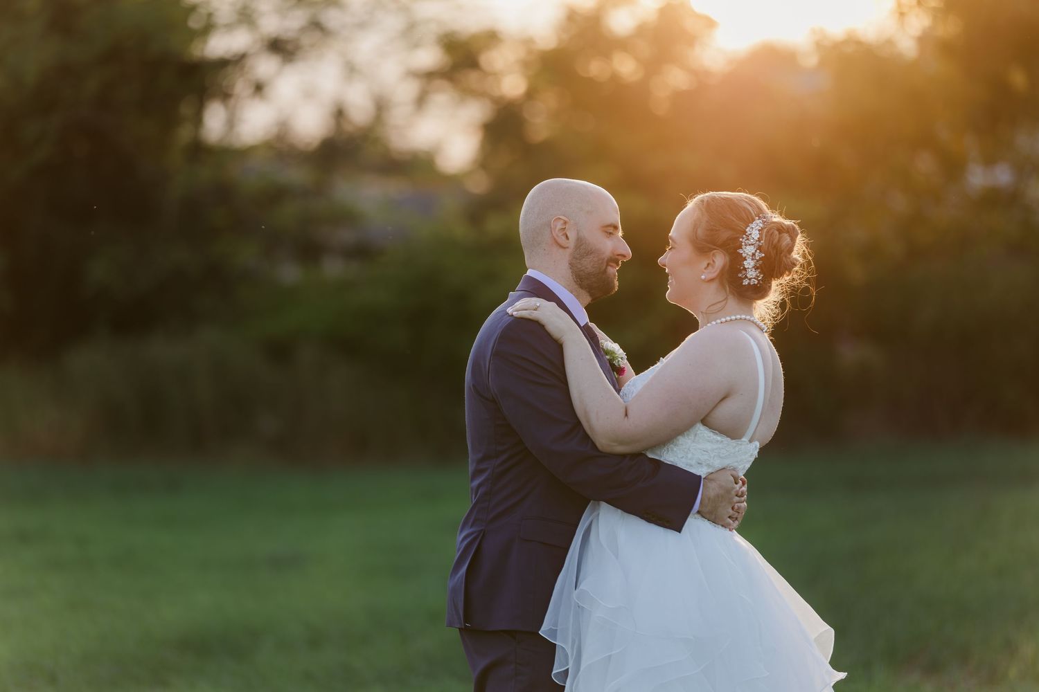 A romantic sunset portrait session in a grassy field with warm golden lighting.