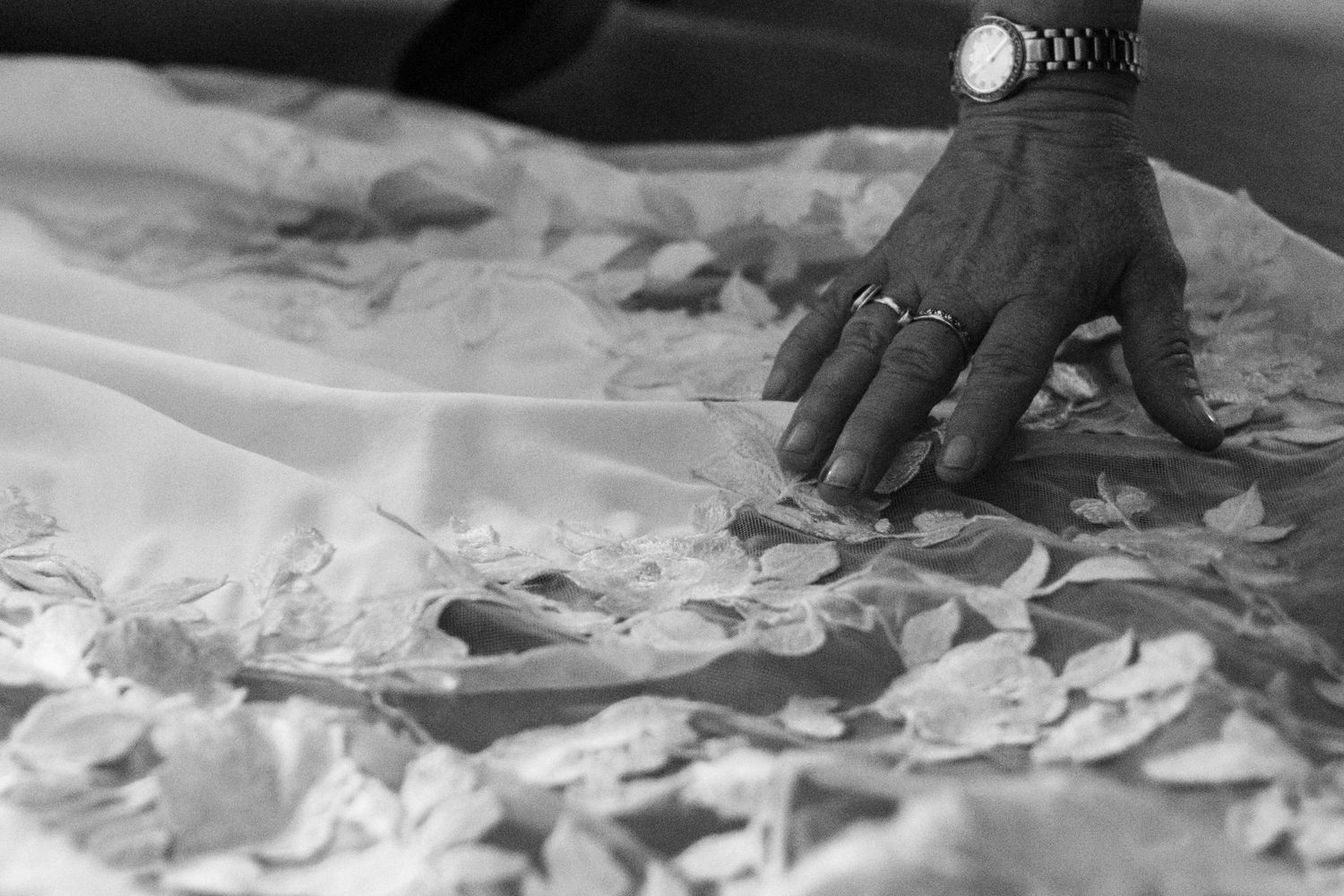 Close-up of Bride's moms hand touching floral lace on the bride's wedding dress