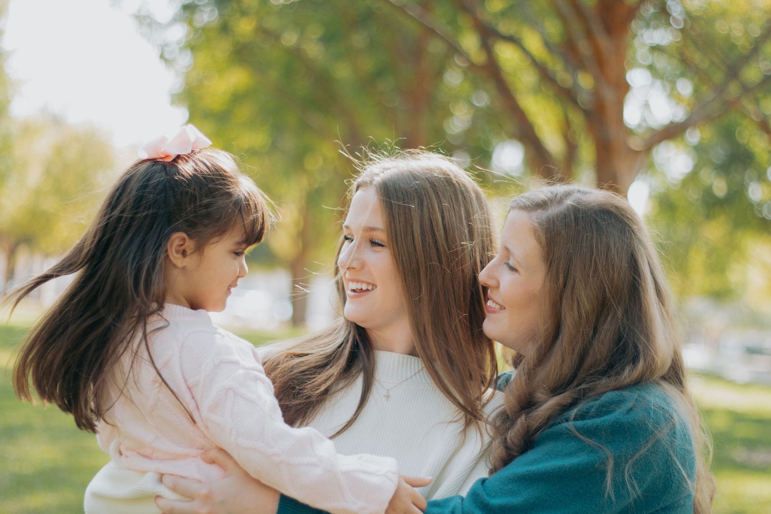 Family members share loving moments together outdoors on a sunny autumn day in matching blue outfits.