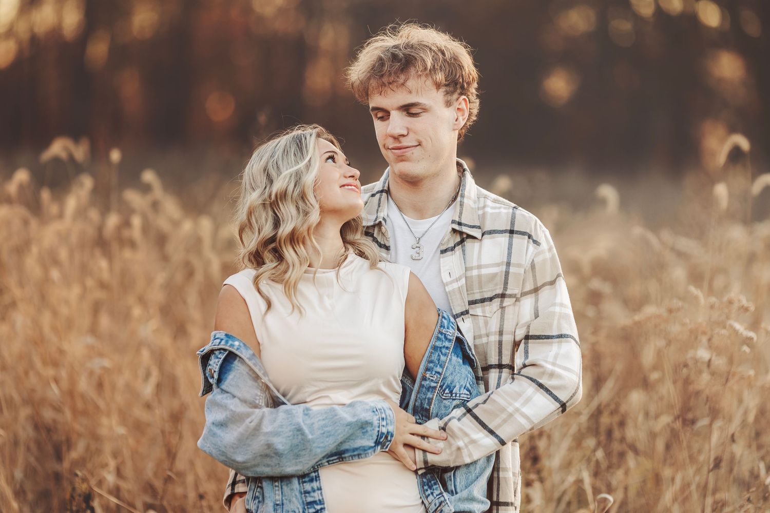 Romantic couple sharing a tender moment in golden autumn sunlight, surrounded by warm fall foliage.