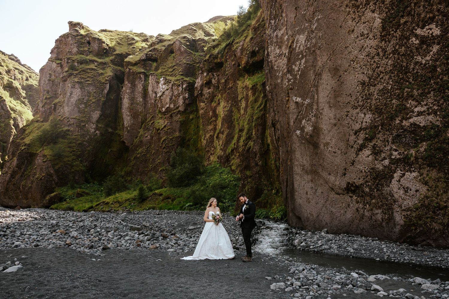 candid moment groom serenading his bride with a ukulele in a moss covered canyon in Þórsmörk (Thórsmörk) during their iceland elopement day