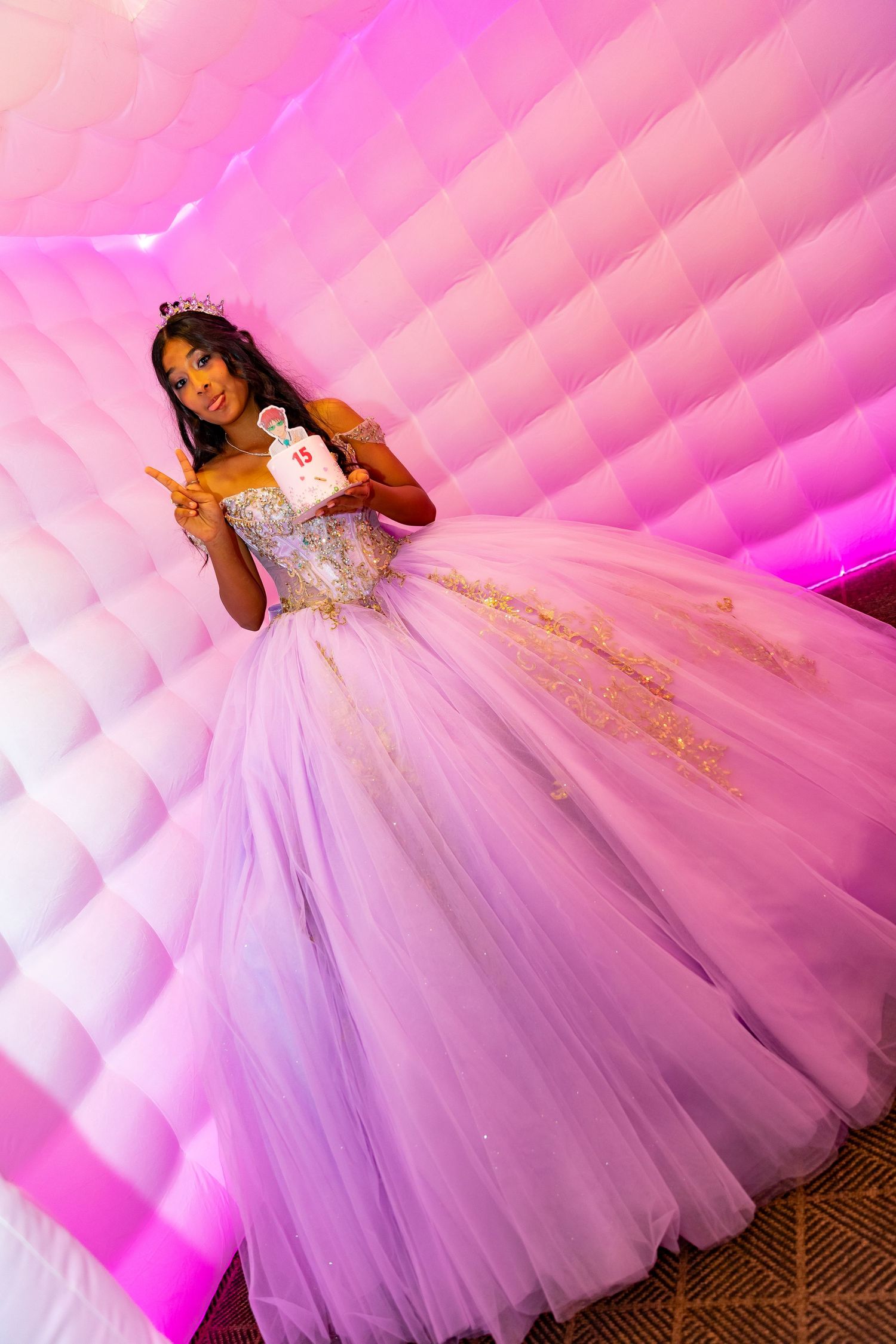 Wedding guests dancing on a wooden dance floor illuminated by vibrant pink and green lighting at a reception party.