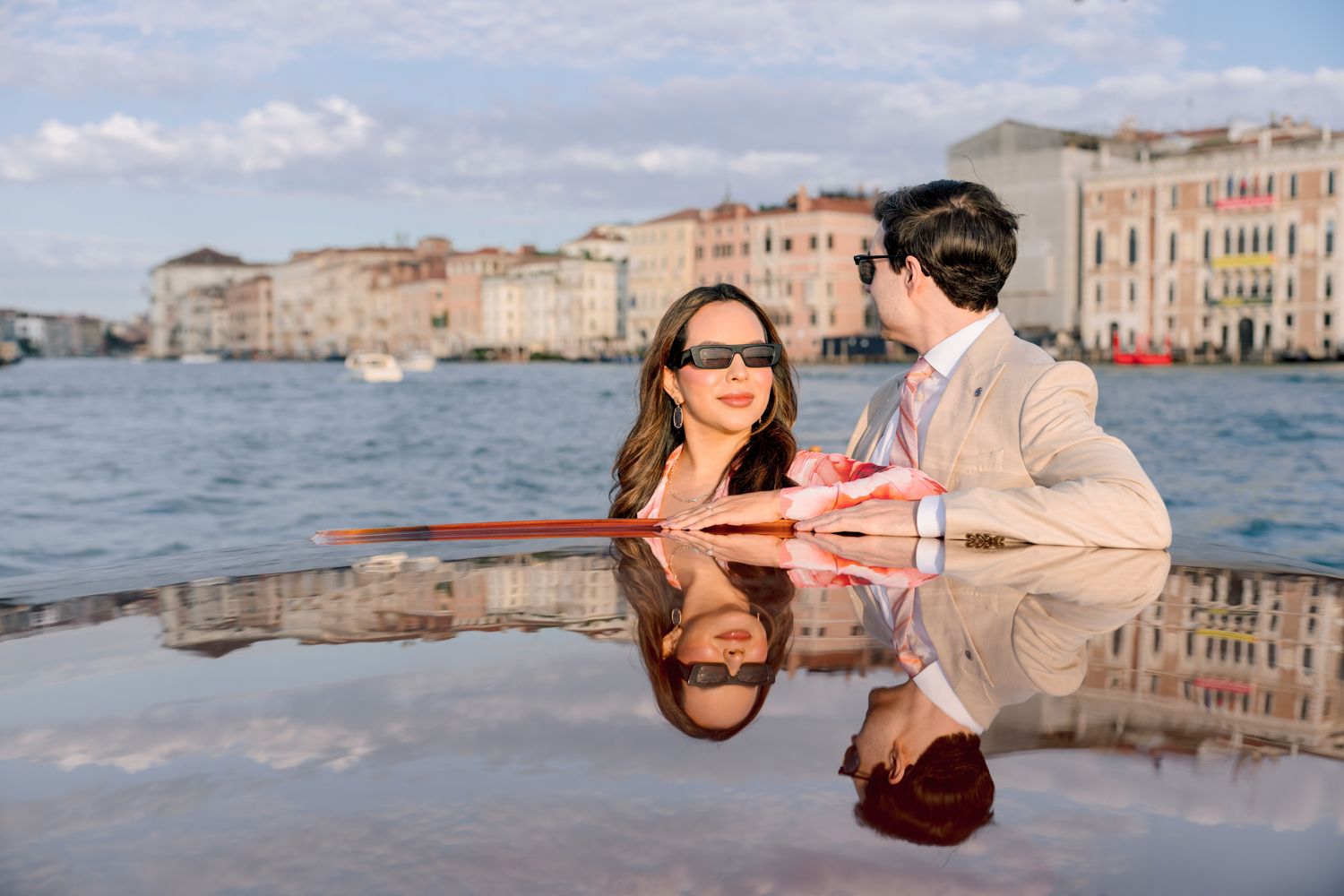 Romantic couple shares tender moments in Venice with gondolas and historic buildings along the canal in the background.