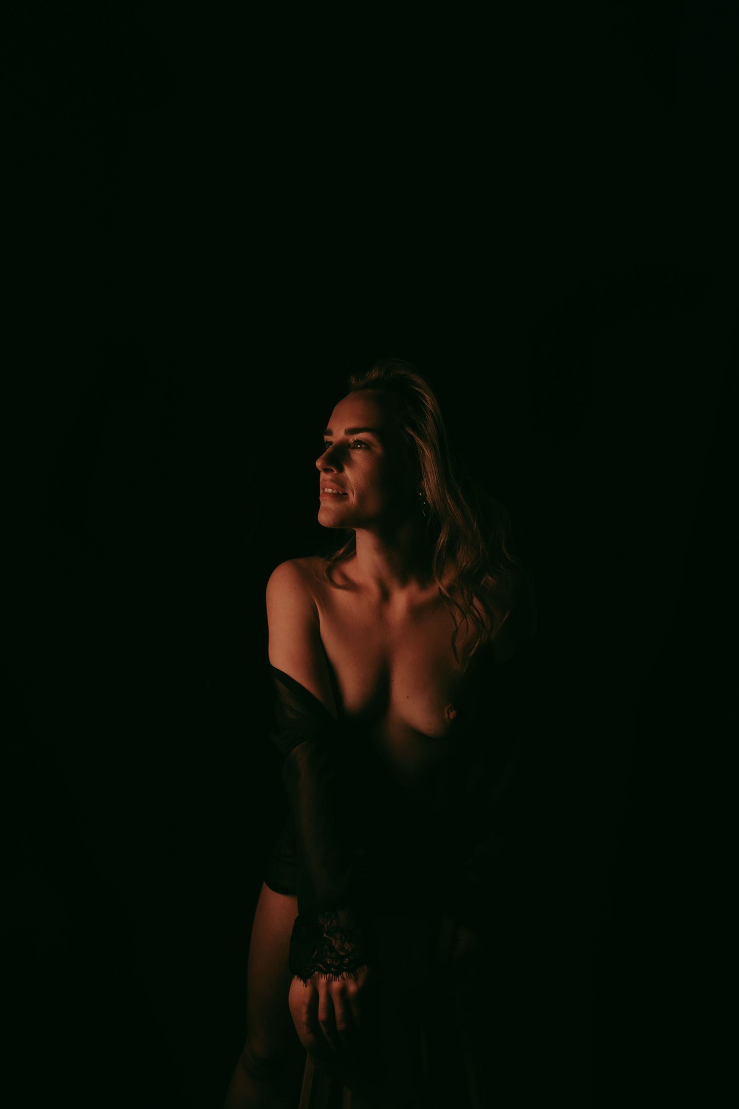 Een vrouw met een donkere achtergrond op de foto. Met een moody stijl kijkend naar de zijkant