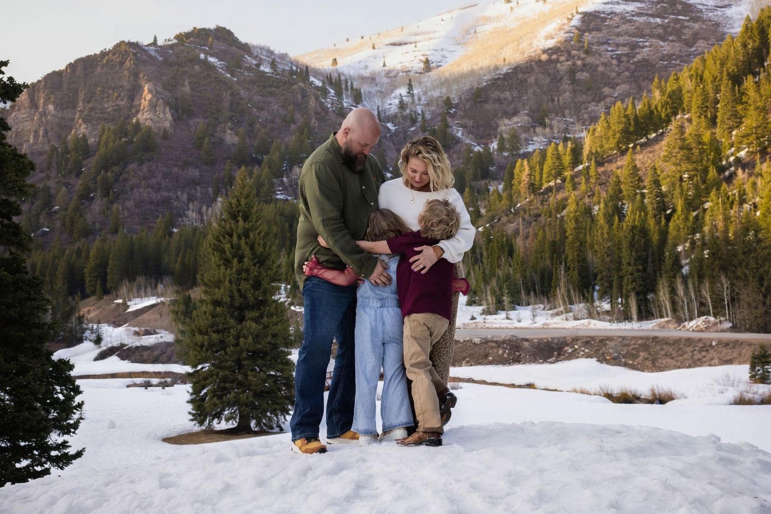 Salt Lake family photographer - family stands close together in a snowy mountain valley at jordan pines in big cottonwood canyon