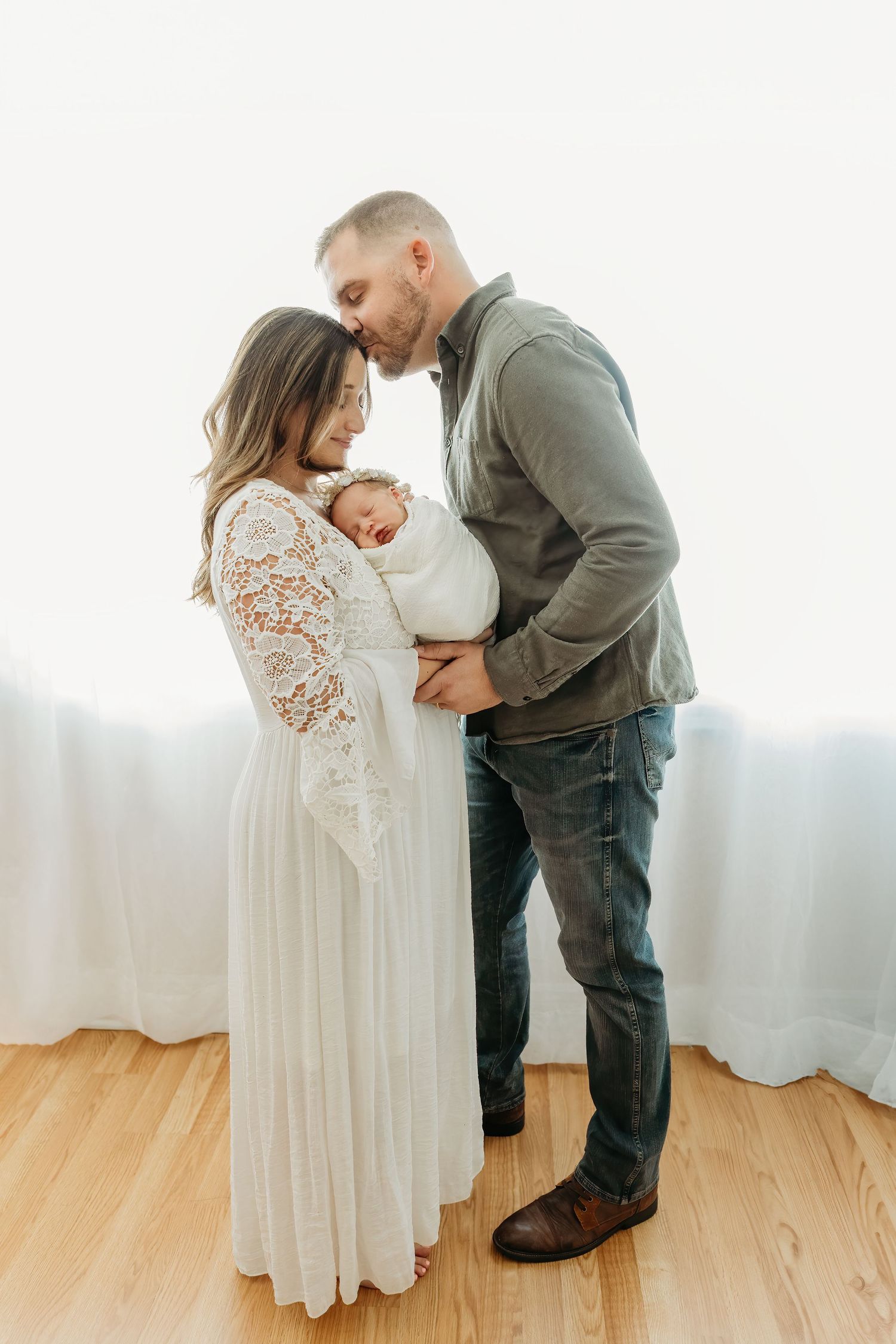 A tender family moment captured indoors as parents embrace their newborn baby during their newborn photoshoot in Tampa, Florida