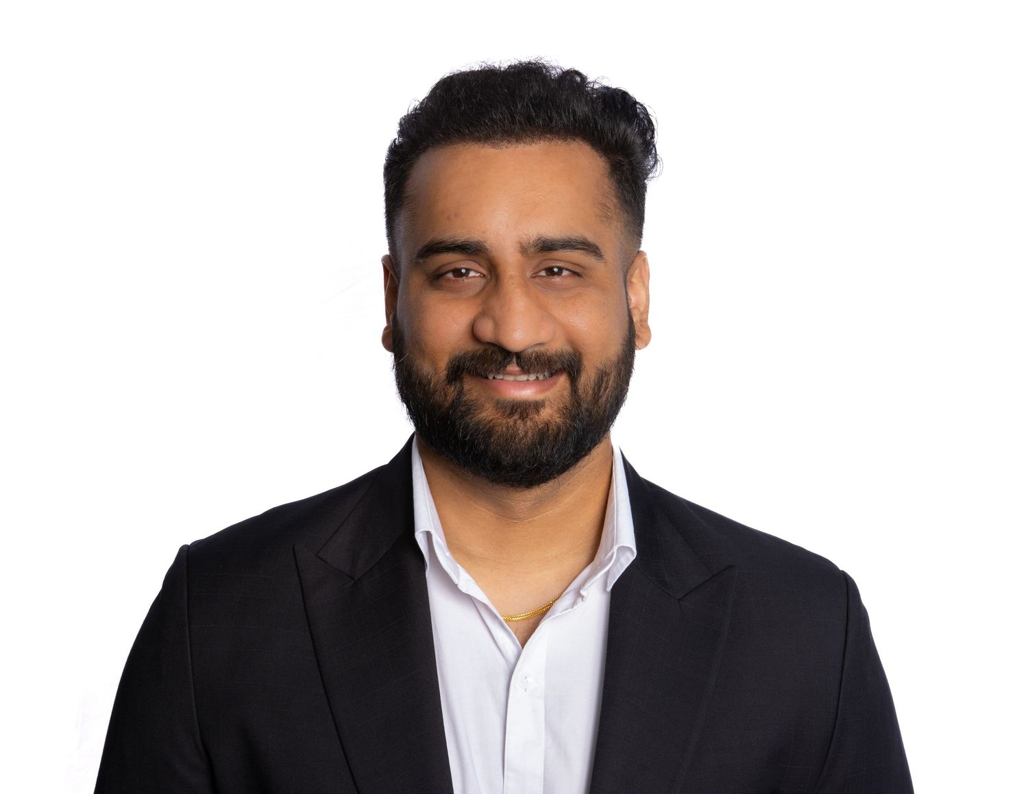 Professional headshot of someone in a black suit jacket and white button-down shirt smiling warmly against a light background.