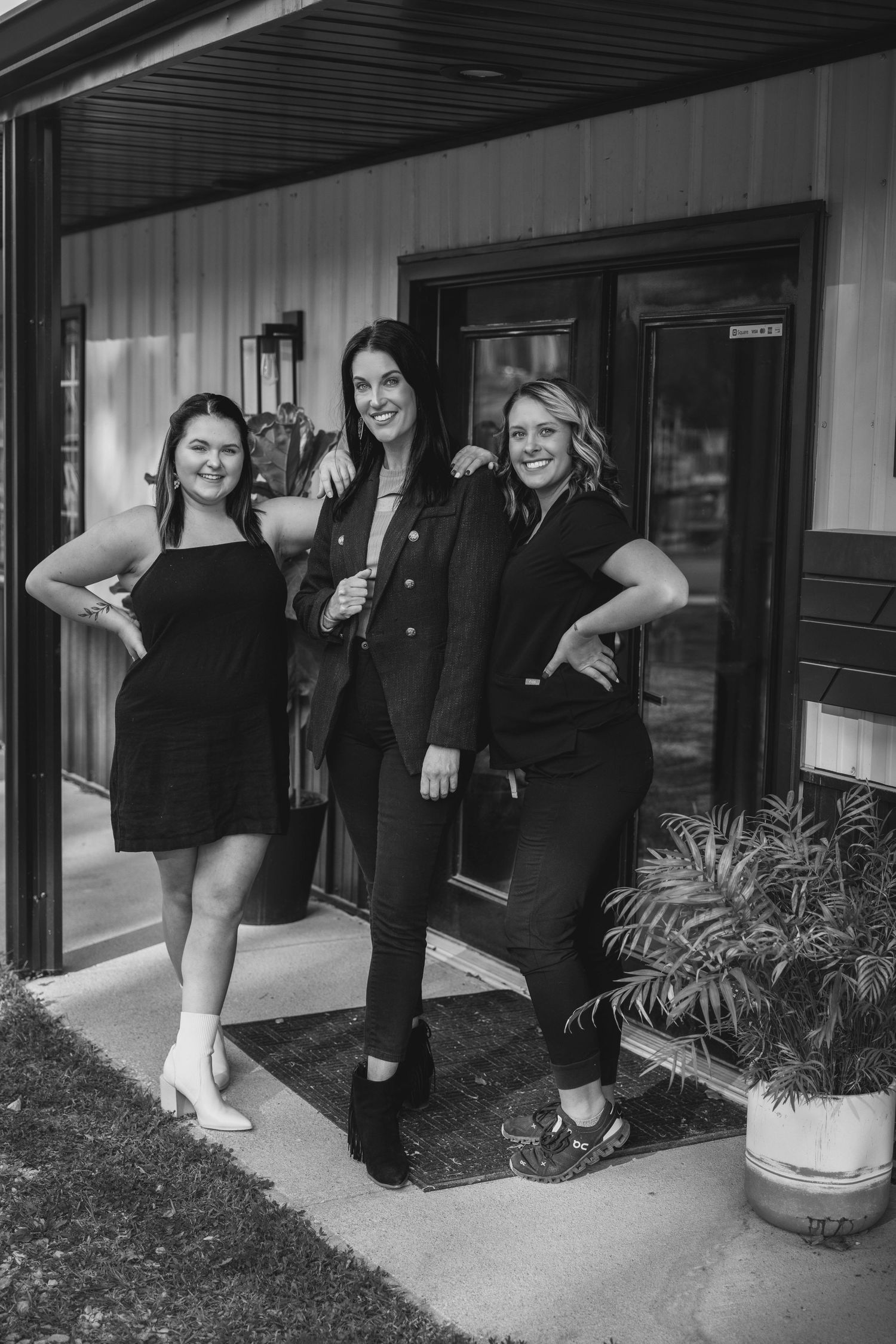 Three friends pose casually on a front porch of a building.