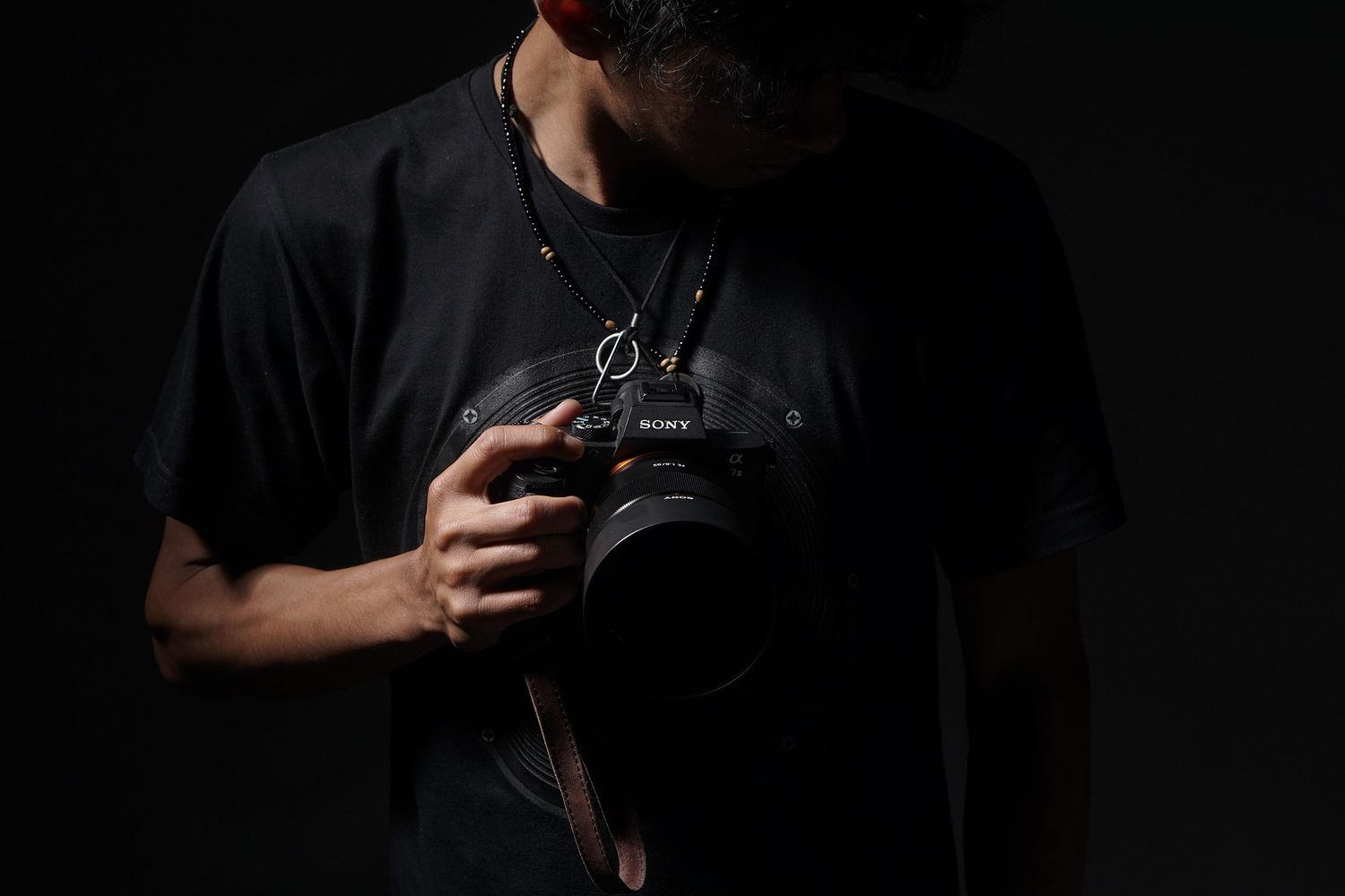 Silhouetted photographer holding camera in dark moody lighting.